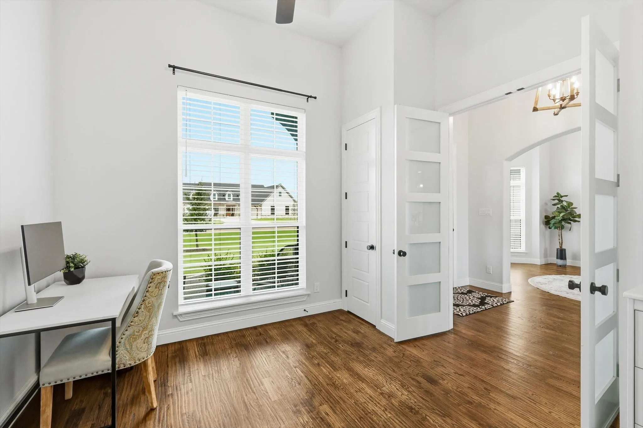 Interior space featuring wood-finish flooring, a large window with white blinds, and white walls
