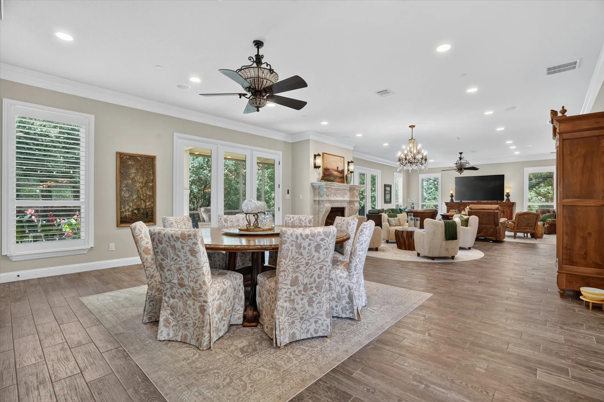 Open-concept living area featuring wood-finish flooring, recessed lighting, and multiple large windows with plantation shutters