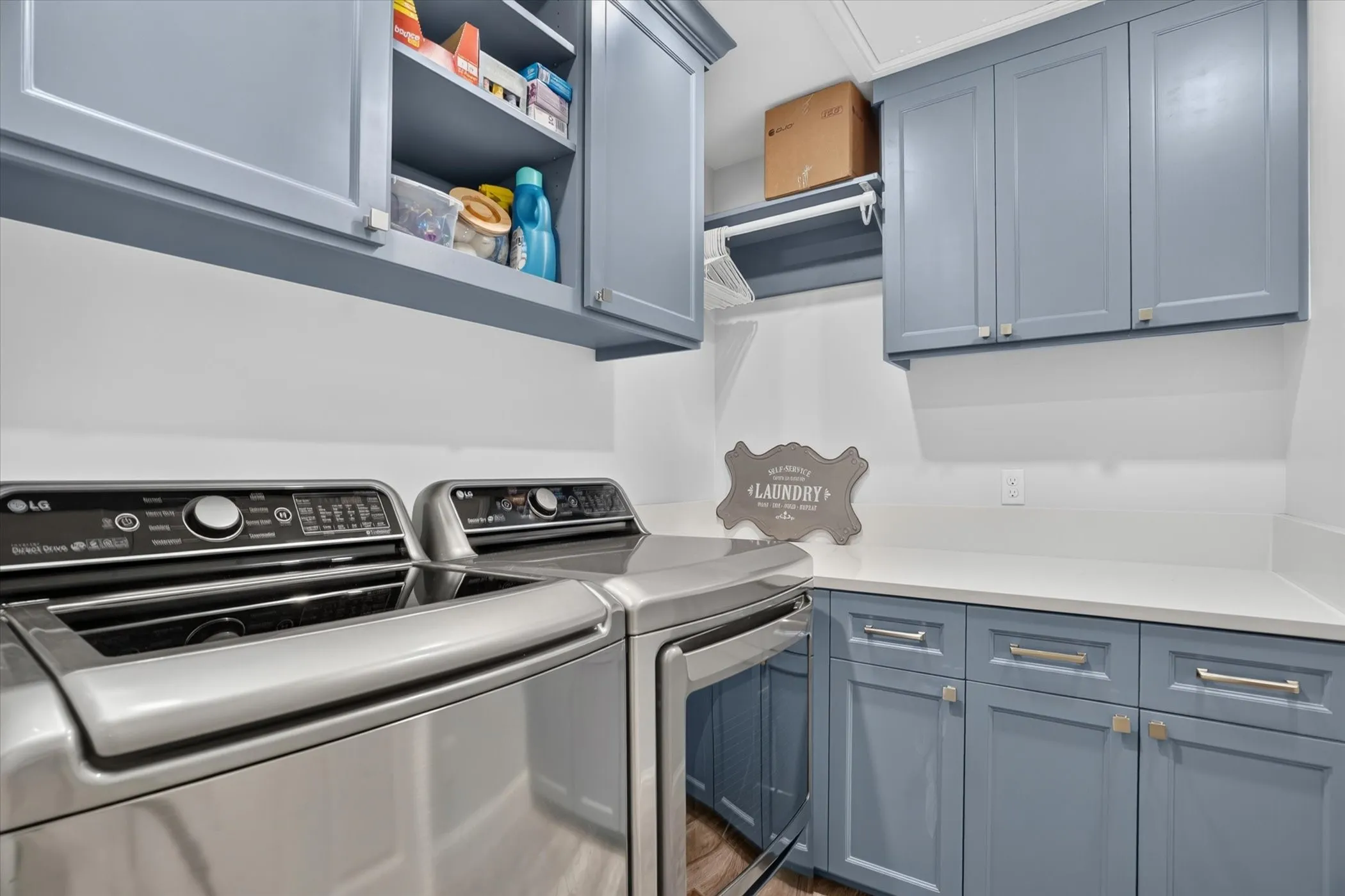Laundry room featuring blue shaker-style cabinetry, white countertops, and wood-finish flooring