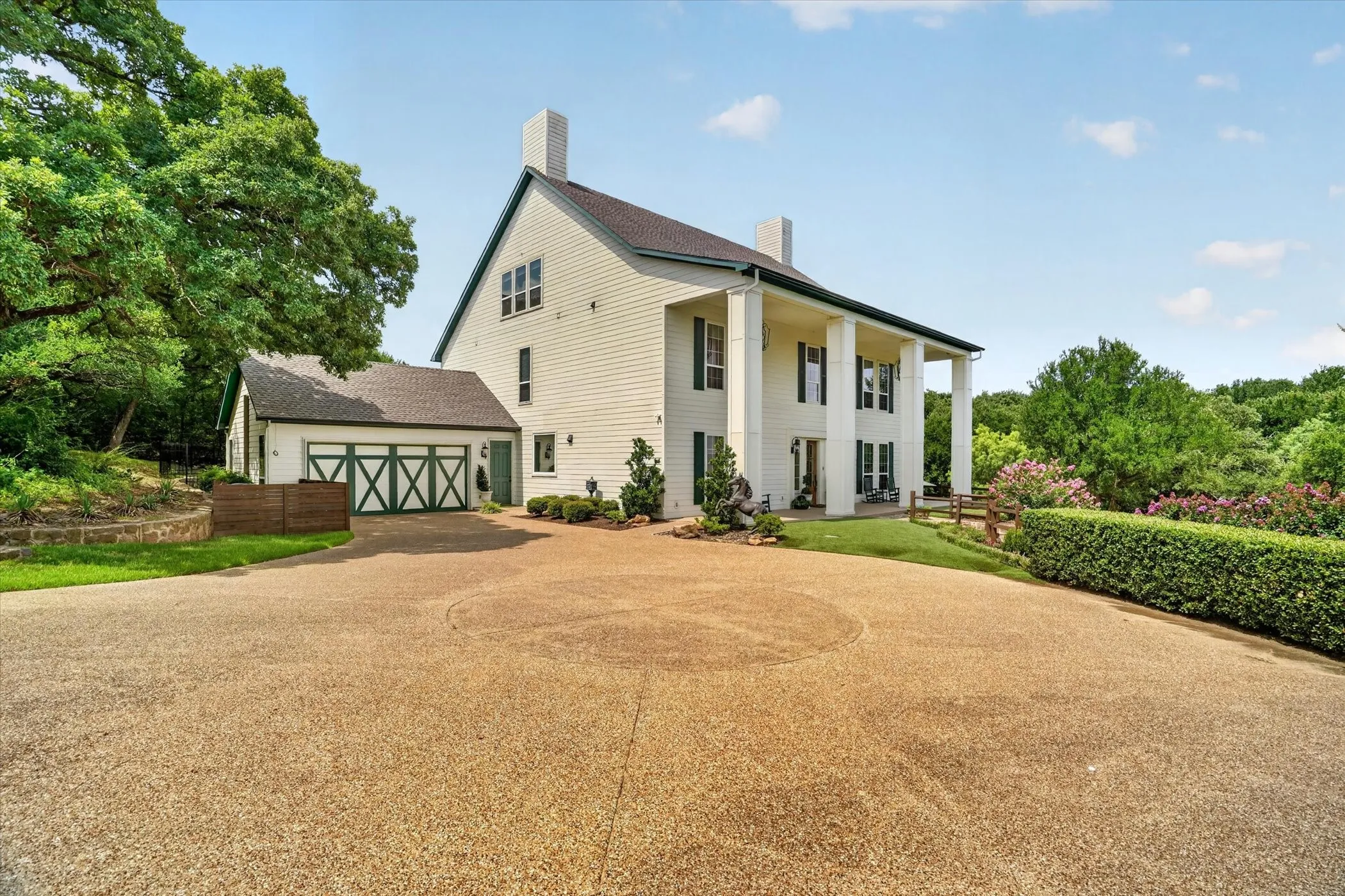 Colonial-style exterior featuring a broad front porch with columns, a prominent driveway, and a three-car garage