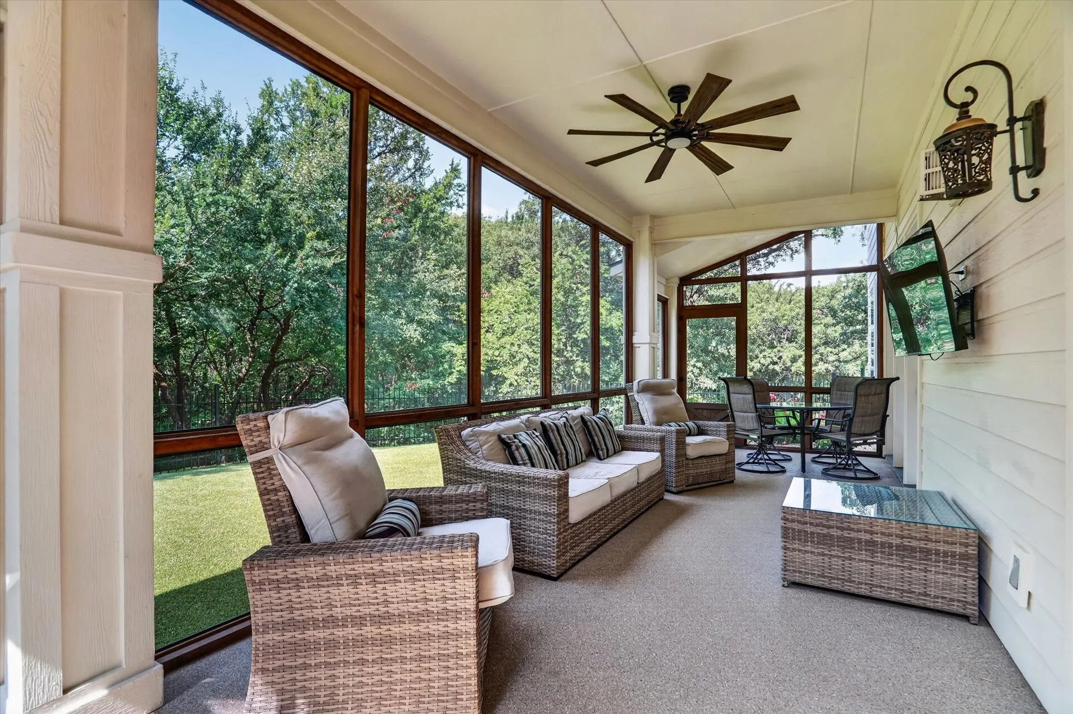 Spacious screened porch featuring a vaulted ceiling, wood-finish ceiling fan, and large windows with dark wood-finish framing
