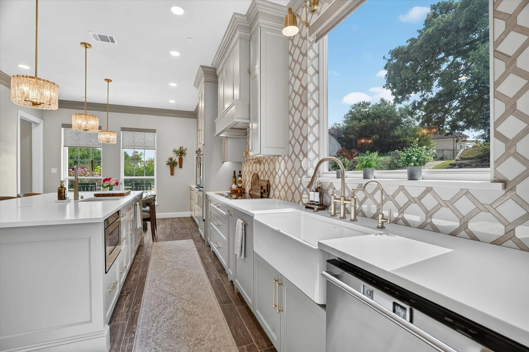 Gourmet kitchen featuring a large farmhouse sink, stainless steel appliances, white cabinetry, quartz countertops, and wood-finish flooring