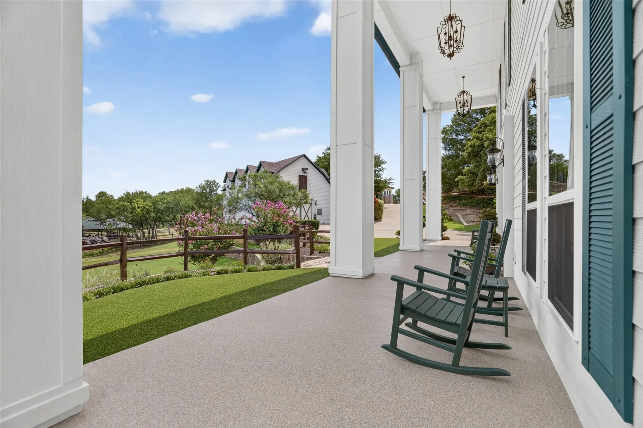 Expansive covered porch featuring substantial white pillars and decorative hanging light fixtures
