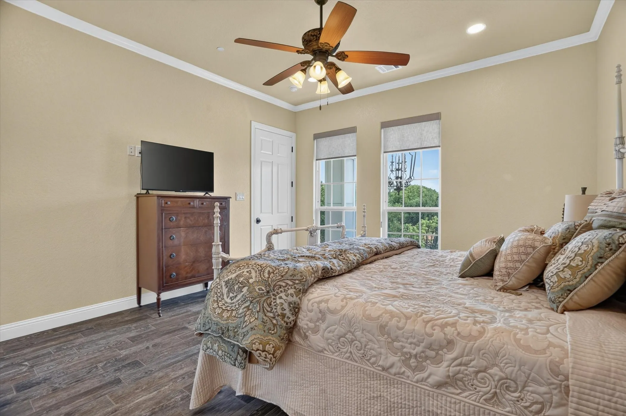 Room featuring wood-finish flooring, two large windows with roller shades, and a ceiling fan with integrated lighting