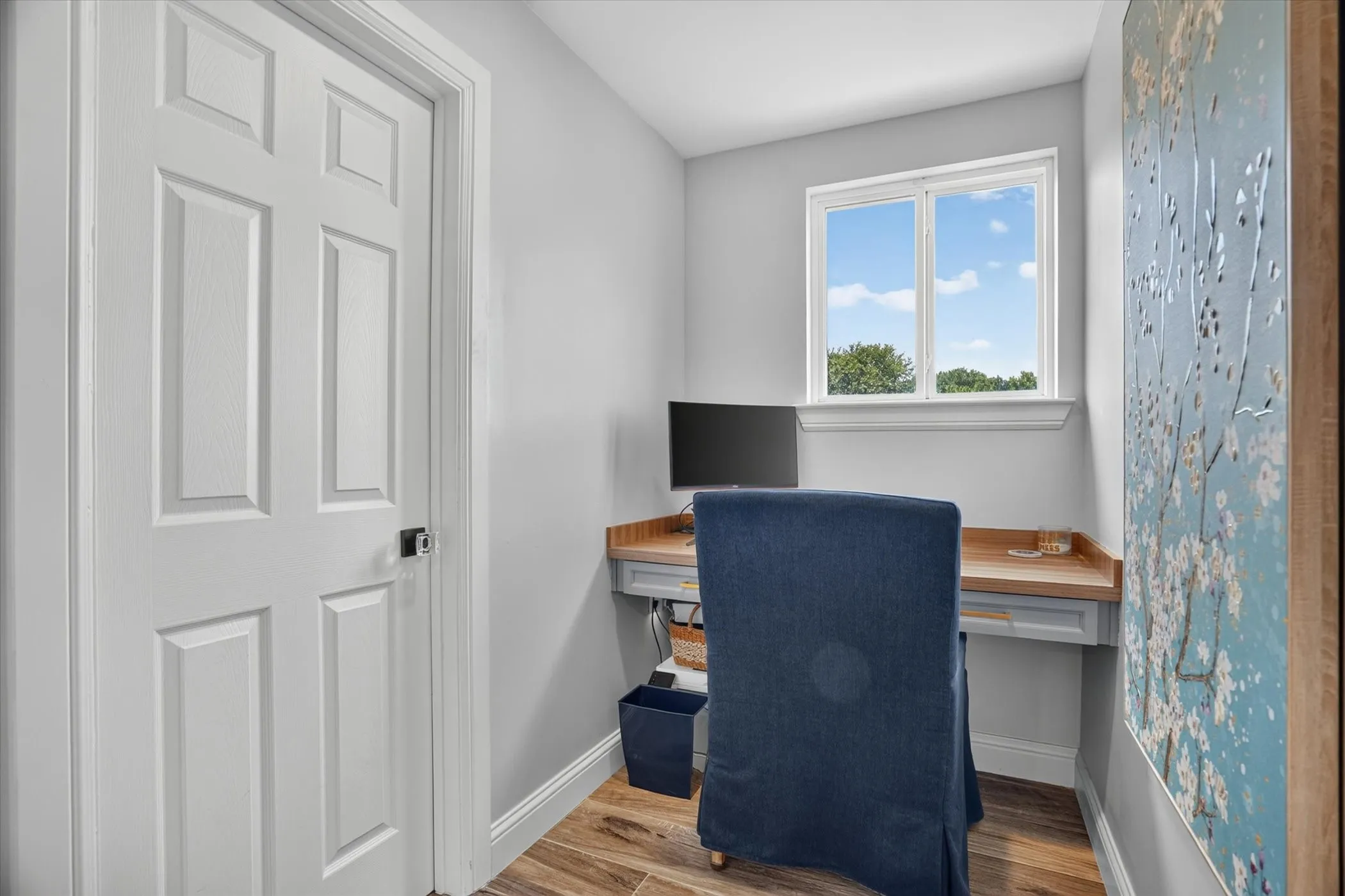 Dedicated workspace featuring a built-in desk with a wood-finish top and gray cabinetry