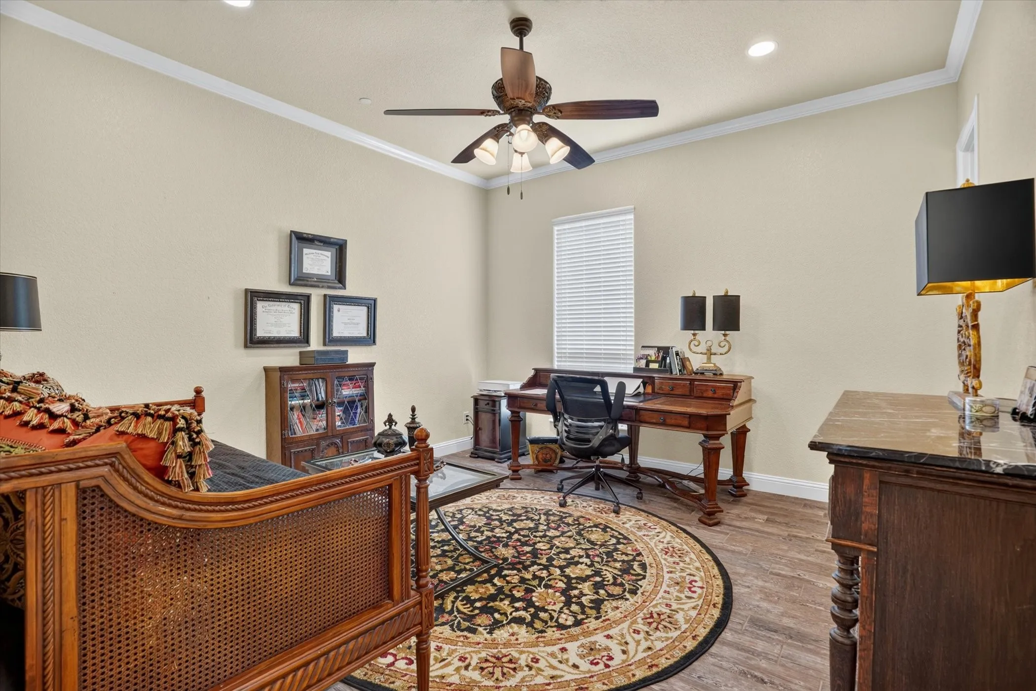 Spacious interior room featuring wood-finish flooring, a ceiling fan with integrated lighting, and crown molding