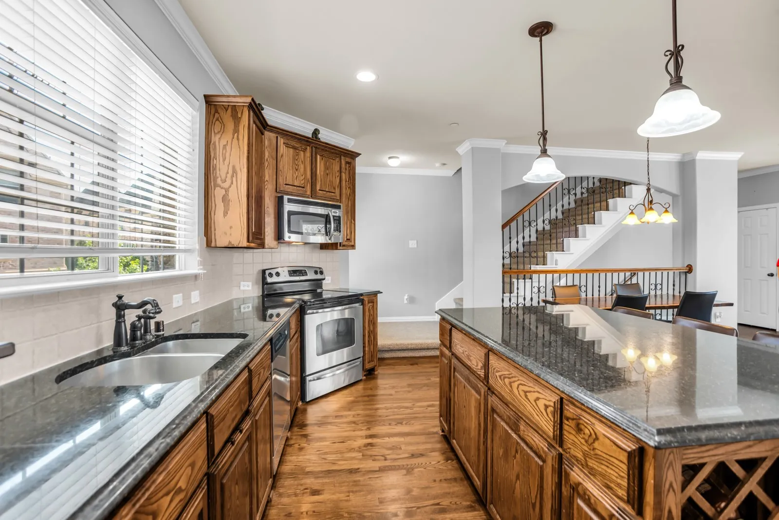 Kitchen featuring wood cabinetry, stainless steel appliances, dark countertops, and wood-finish​​‌​​​​‌​​‌‌​‌‌​​​‌‌​‌​‌​‌​​​‌​​ flooring