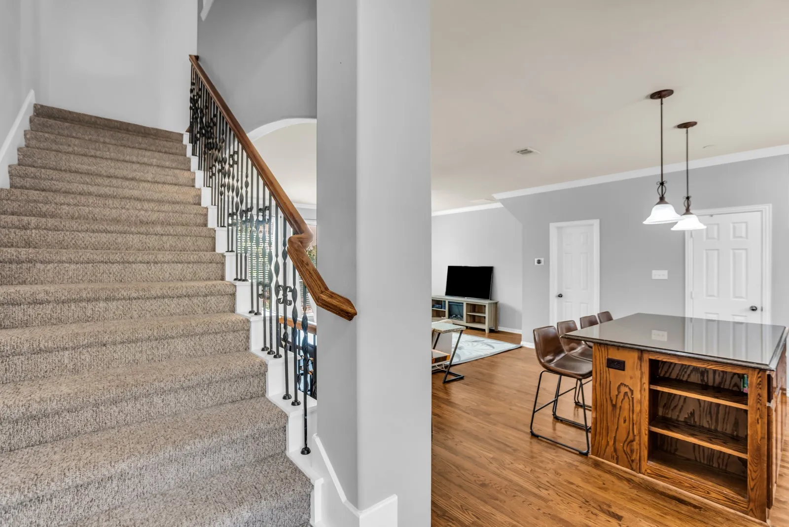 Carpeted staircase with wrought iron balusters and a wood handrail