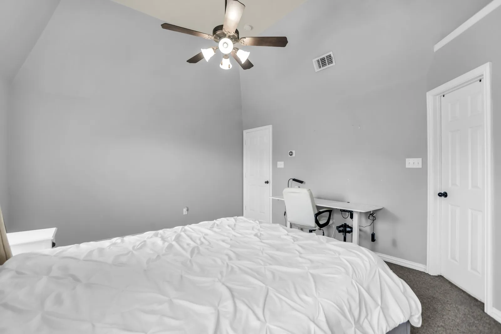 Room featuring a vaulted ceiling with a ceiling fan, light gray wall paint, and carpet flooring