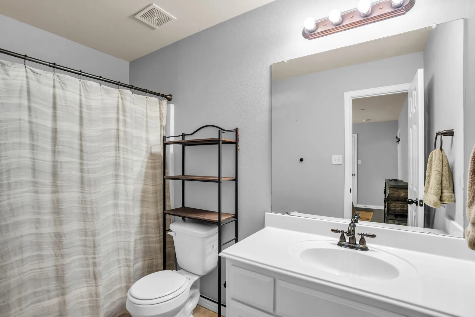 Bathroom featuring a white vanity with an integrated sink, polished chrome faucet, and a large wall-mounted mirror