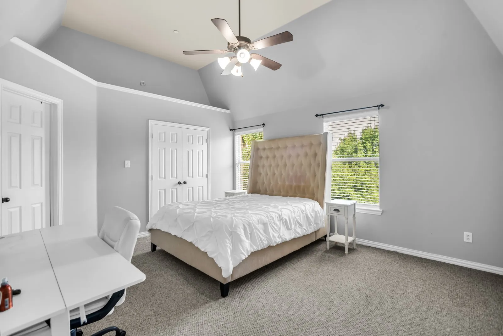Carpeted room featuring a vaulted ceiling and two windows with blinds