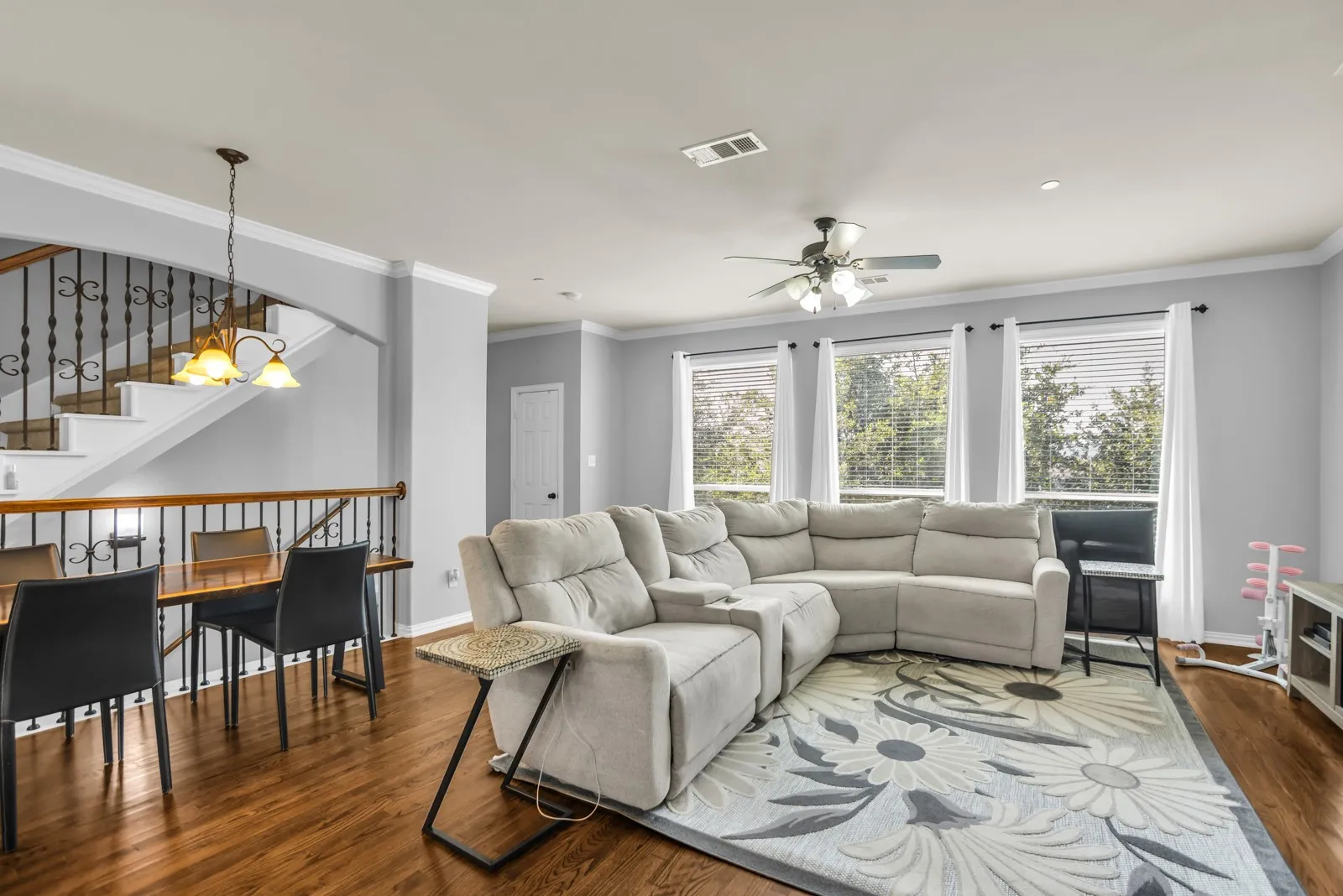 Open-concept living space with dark wood-finish flooring, multiple windows, and a ceiling fan
