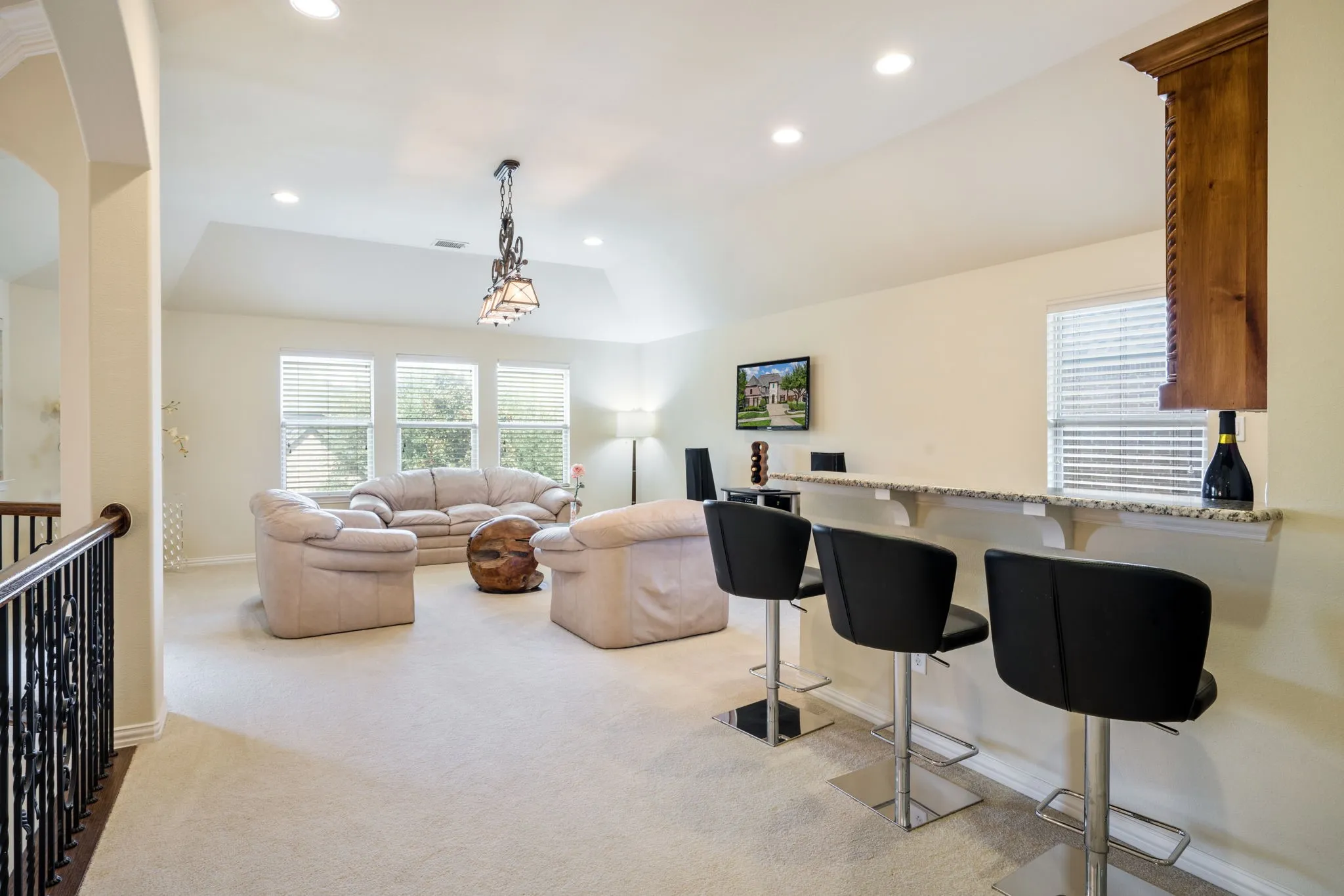 Spacious upper-level landing with carpeted flooring, decorative wrought iron railing, and recessed lighting