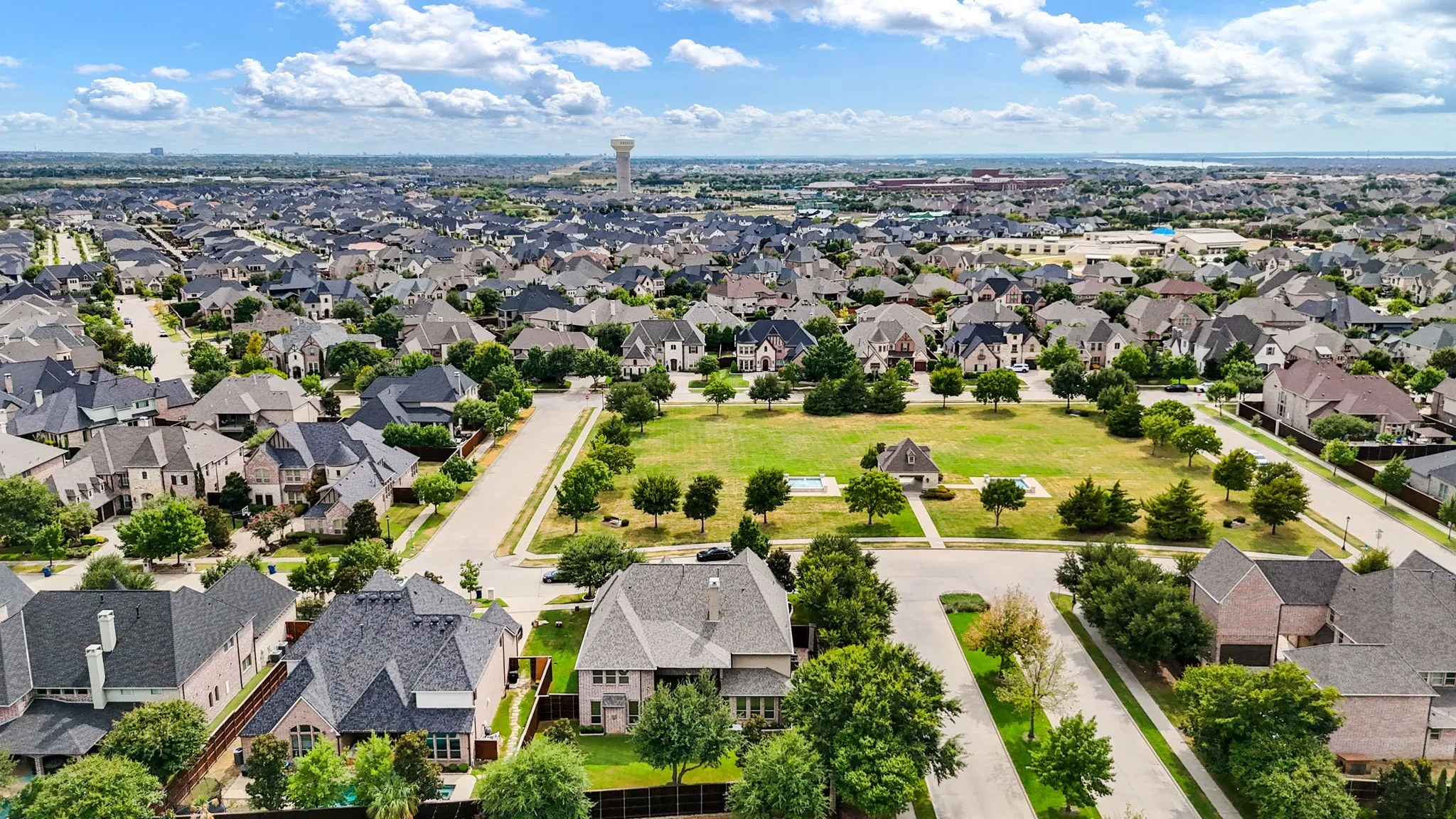 Expansive neighborhood featuring numerous residential properties, abundant green spaces, and a prominent water tower in the distance