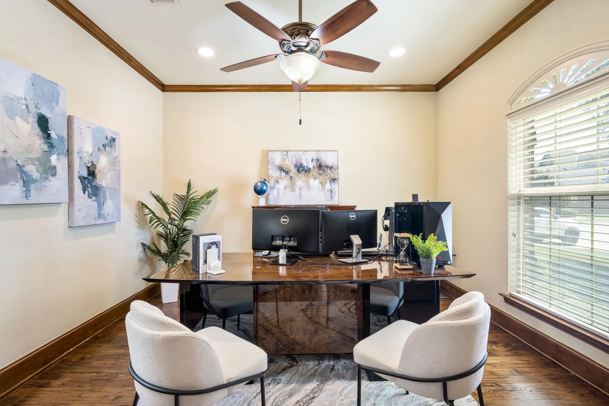 Wood-finish flooring, crown molding, arched window with blinds, and a built-in ceiling fan with integrated lighting