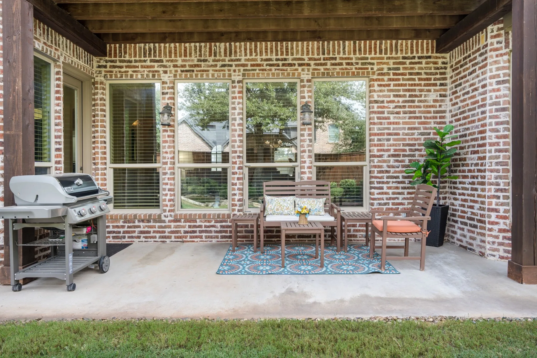 Expansive backyard featuring a manicured lawn, brick exterior, two-story covered patio, and privacy fencing