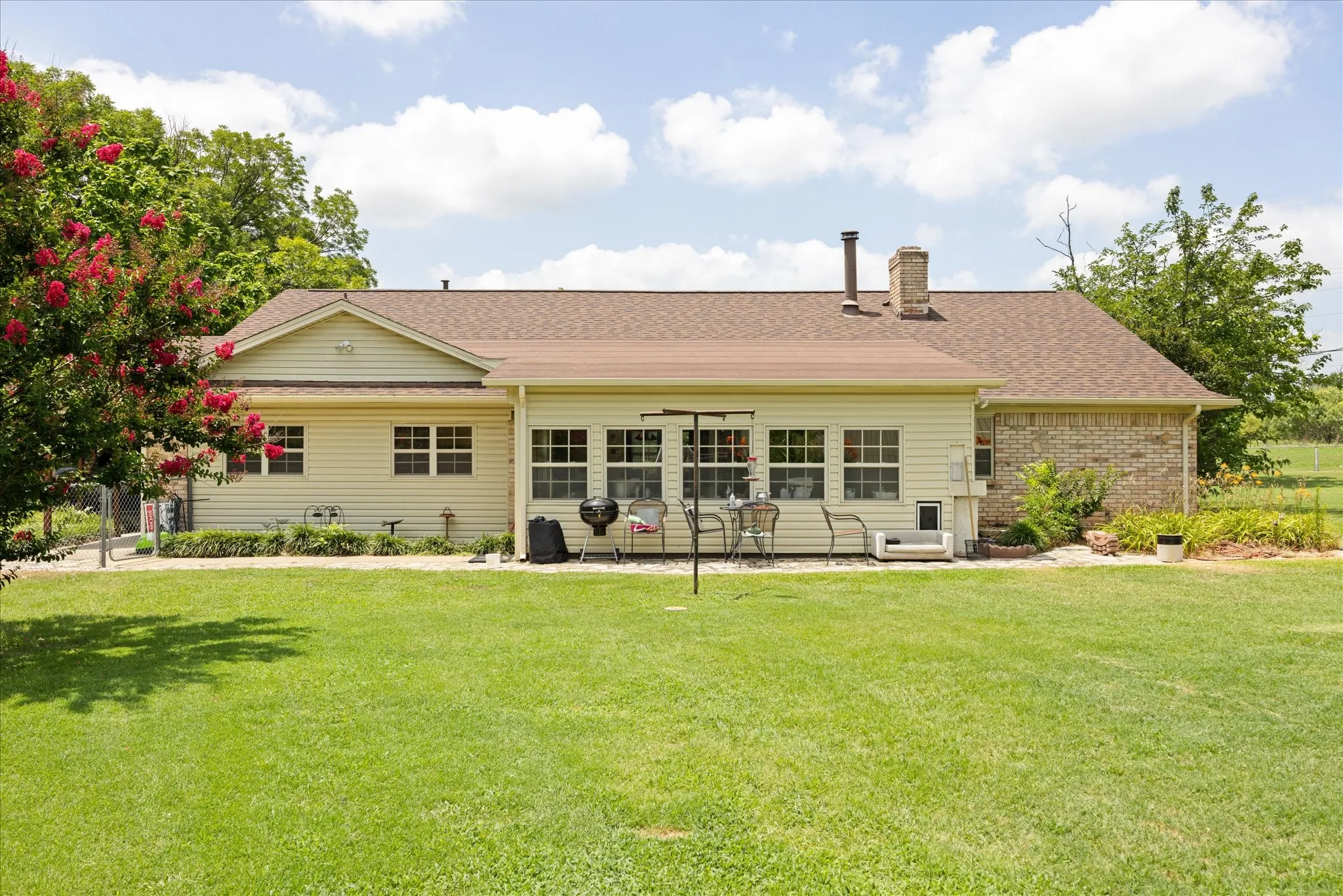 Expansive rear lawn with a cream-colored siding and brick facade