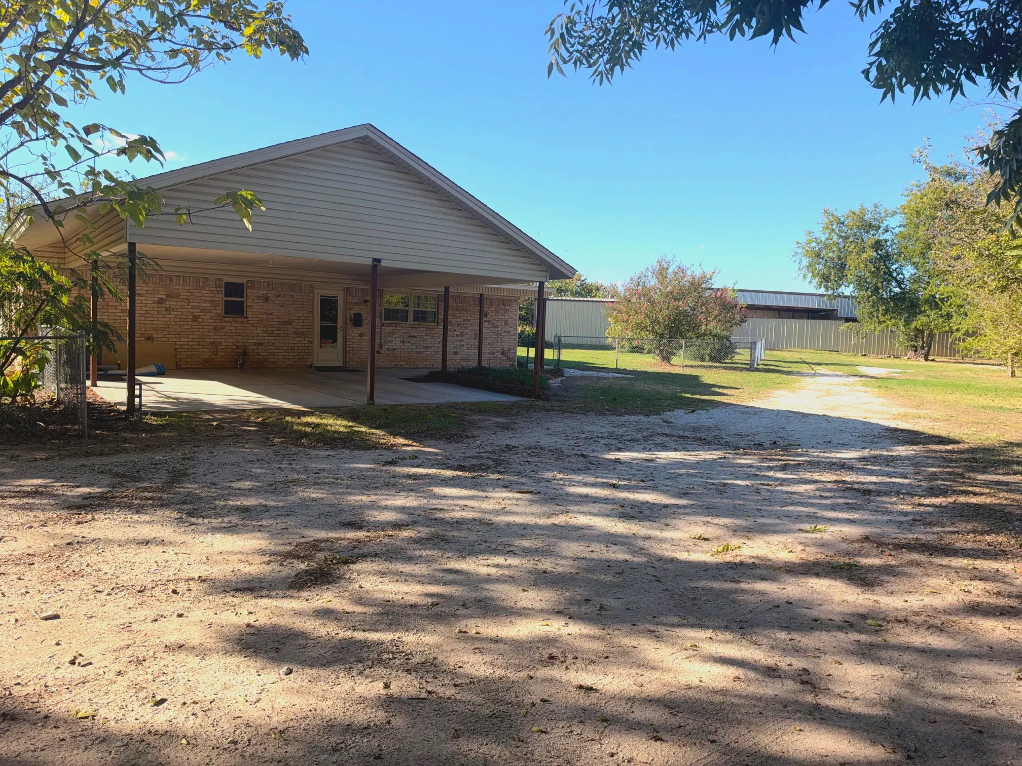 Brick exterior with a covered concrete patio and a metal fence