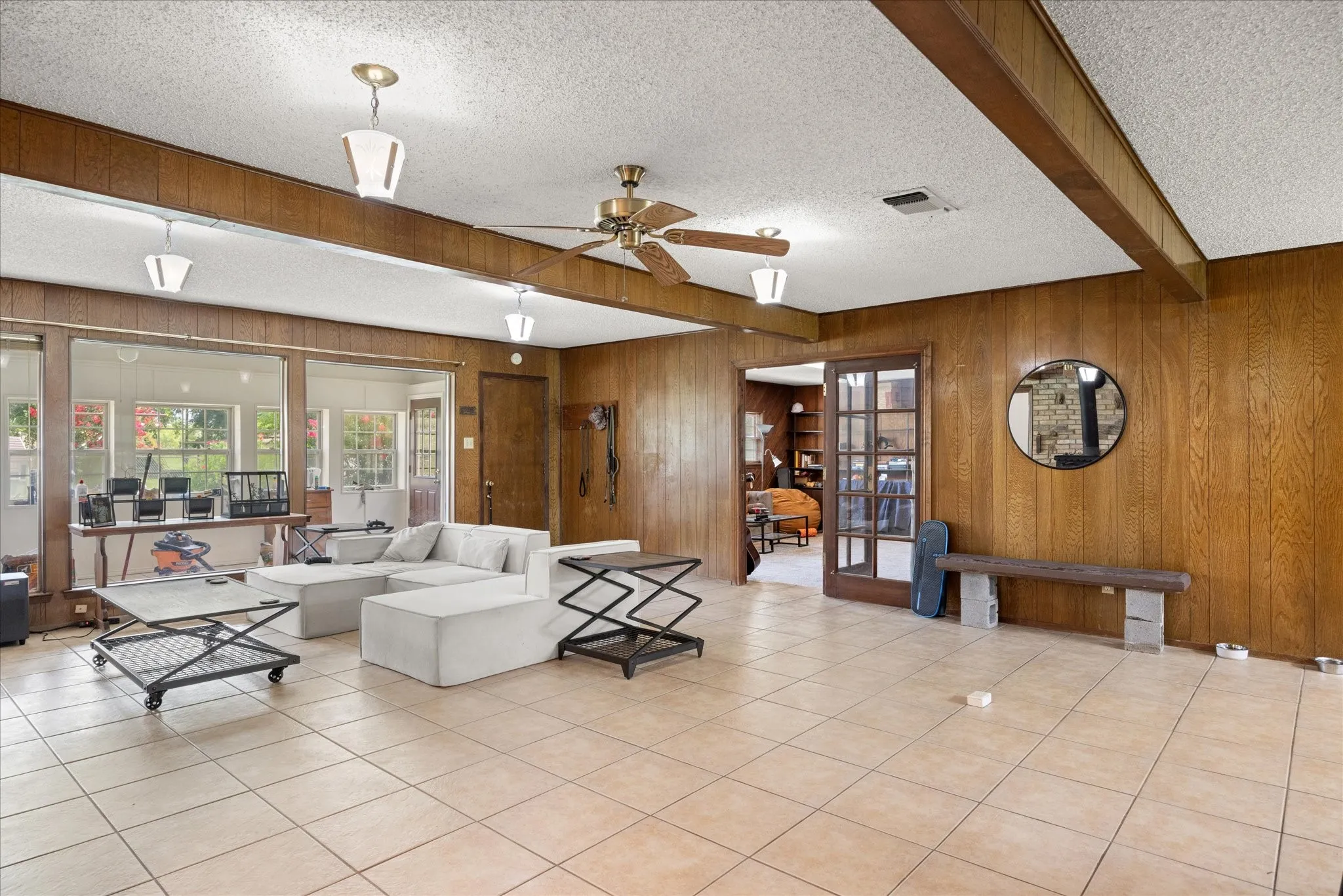 Tile flooring throughout this spacious room, featuring wood-paneled walls and a ceiling fan