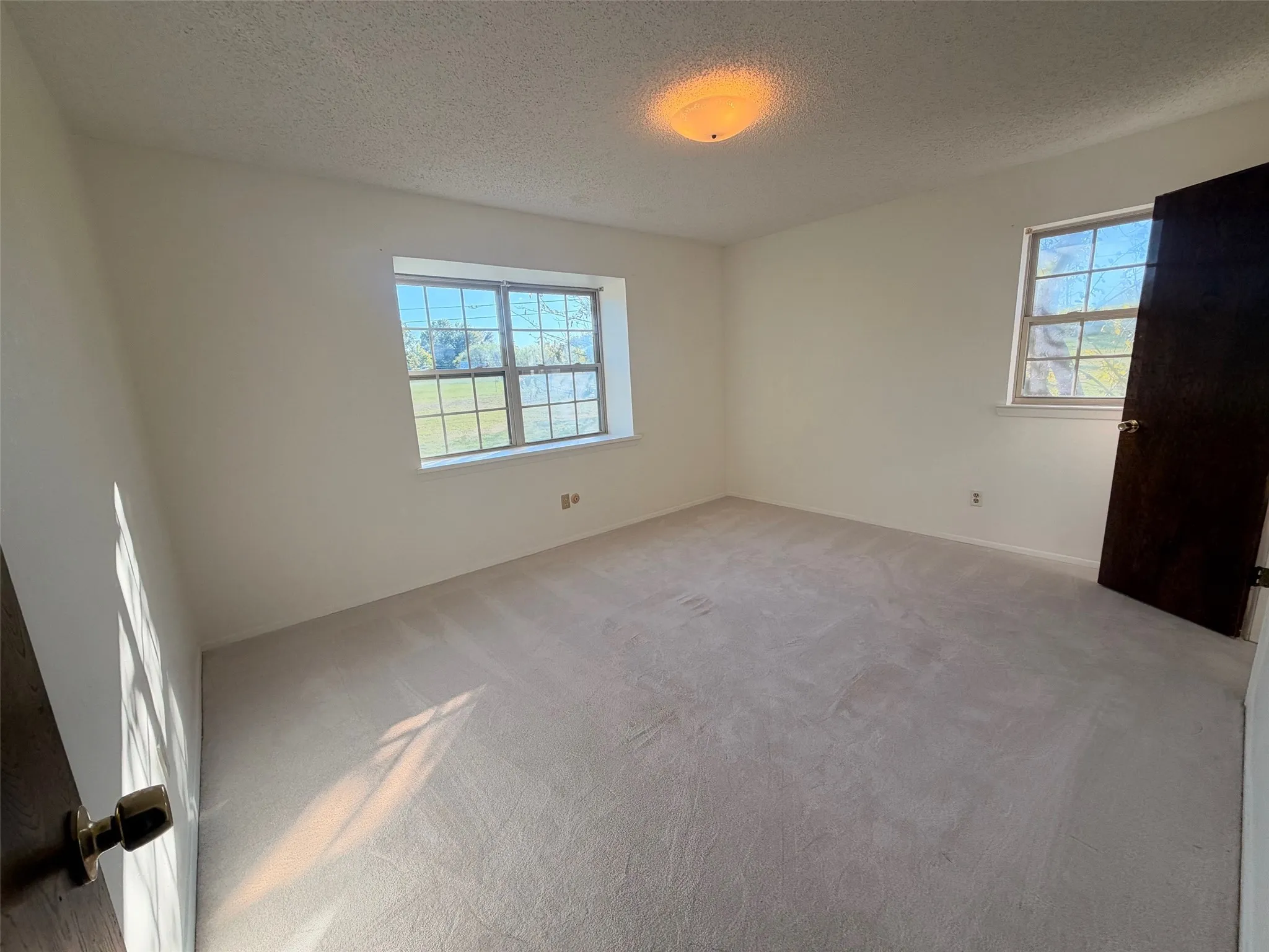 Carpeted bedroom with a single window and an overhead flush-mount light fixture
