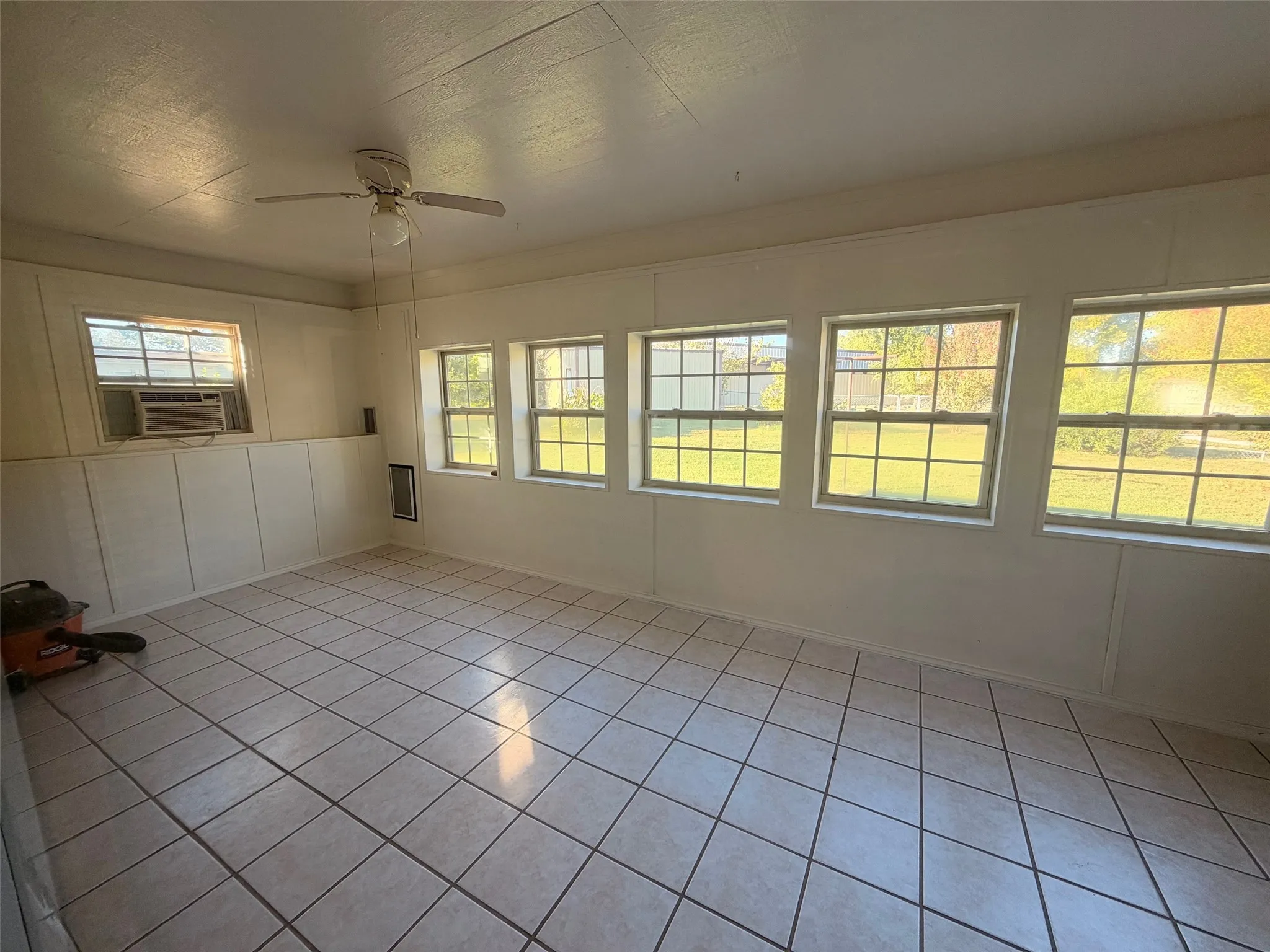 Room featuring a ceiling fan, multiple windows, and tiled flooring