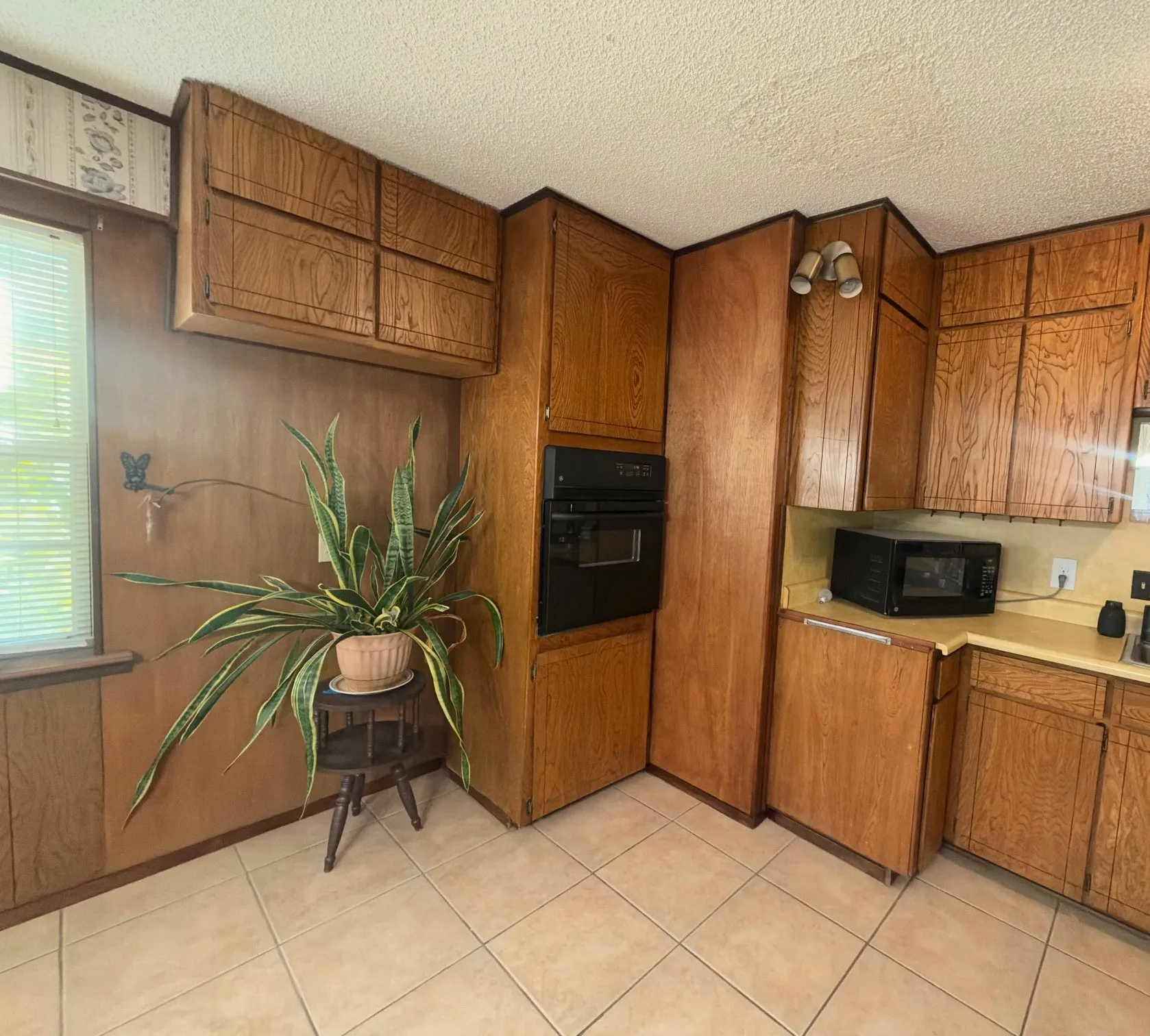 Built-in wall oven, extensive wood cabinetry, tiled flooring, and corner countertop