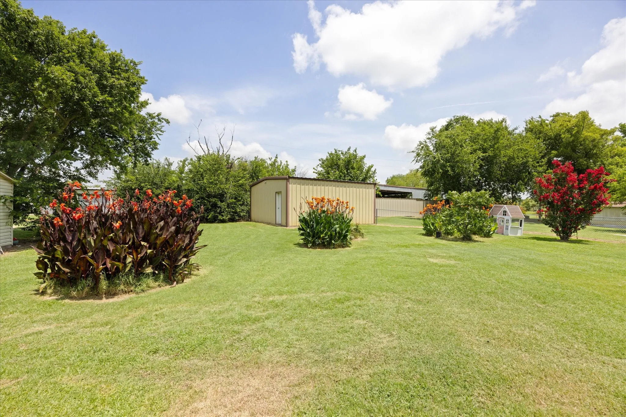 Expansive green lawn with mature trees and established garden beds