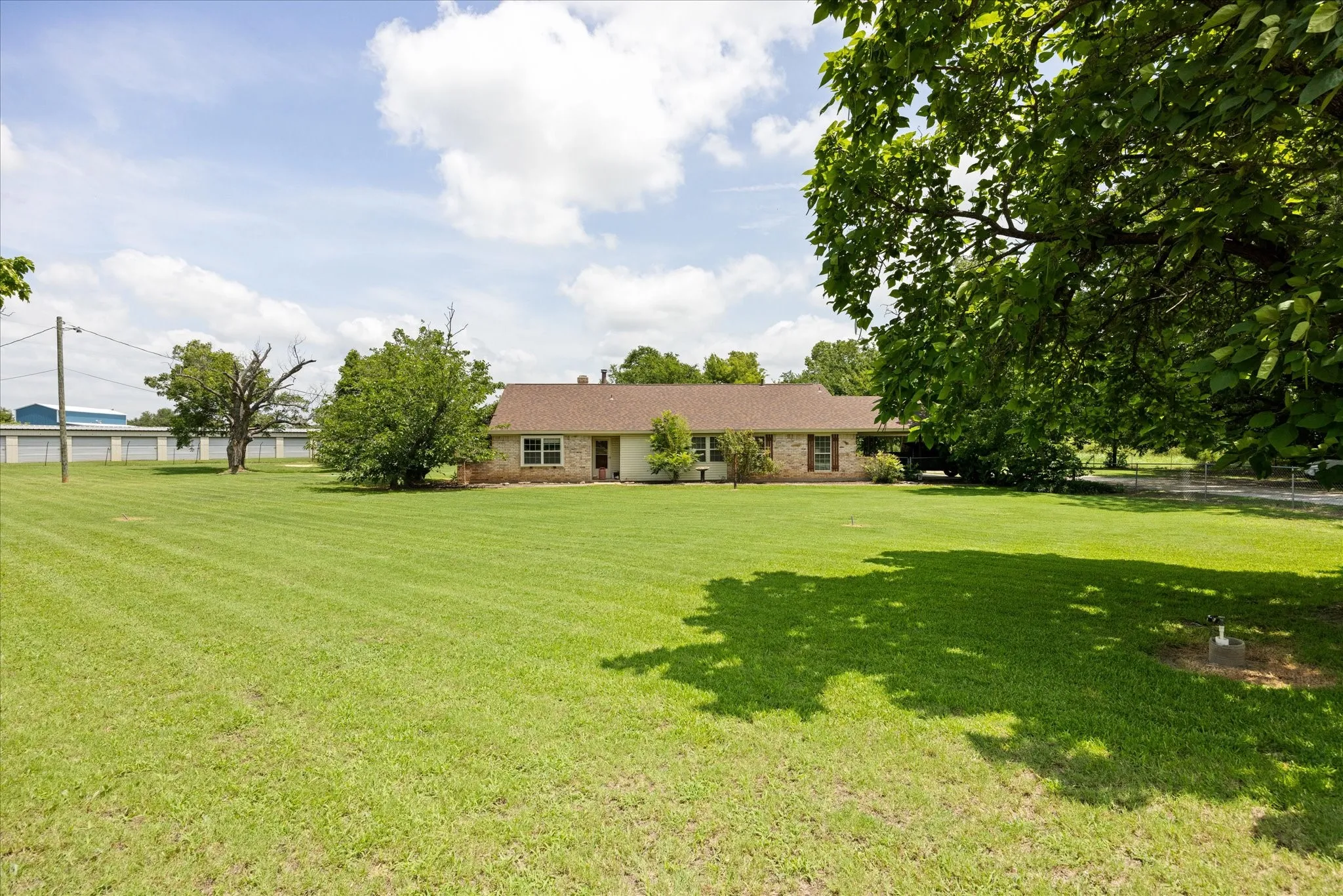 Ranch-style residence featuring a brick facade, covered carport, and a brown shingle roof