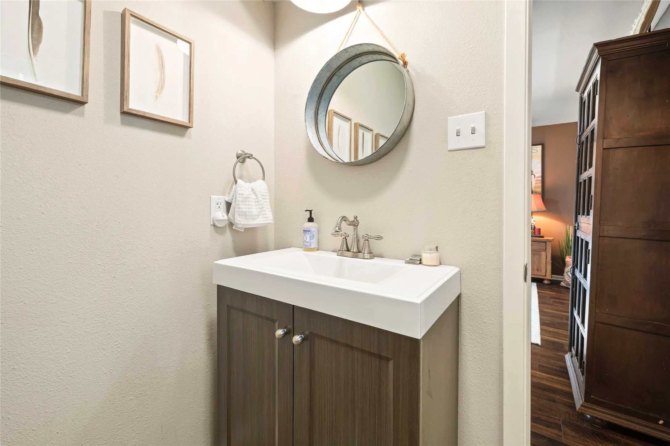 Bathroom vanity featuring a rectangular sink, wall-mounted faucet, and wood-finish cabinetry