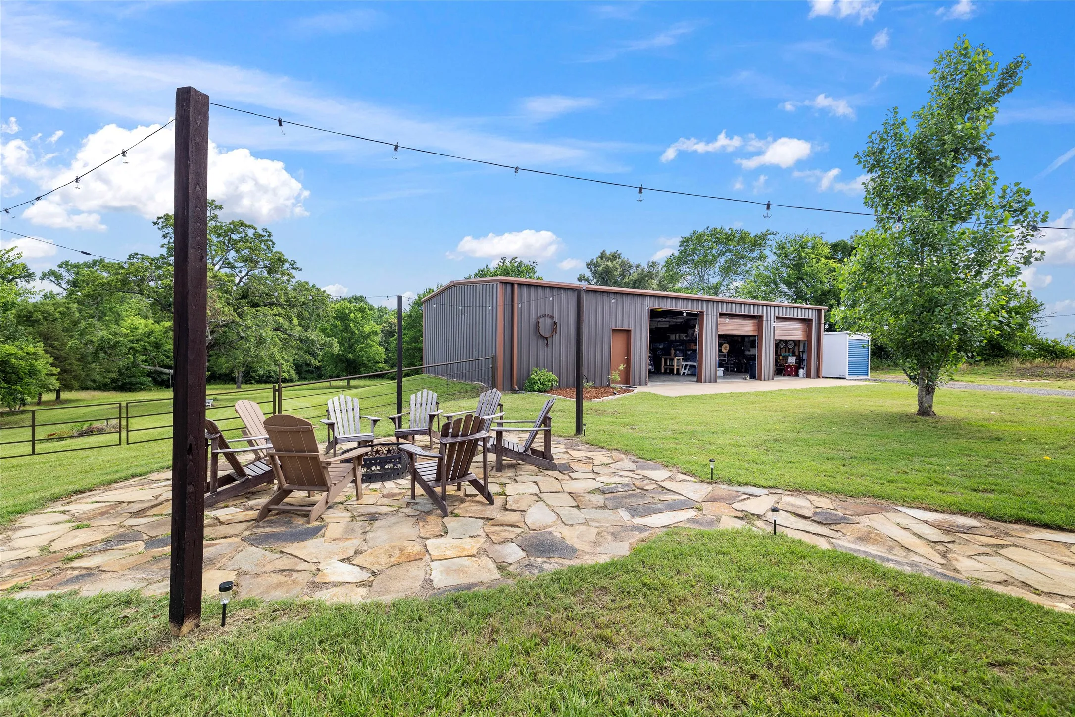 Outdoor flagstone patio with a central fire pit, surrounded by Adirondack chairs