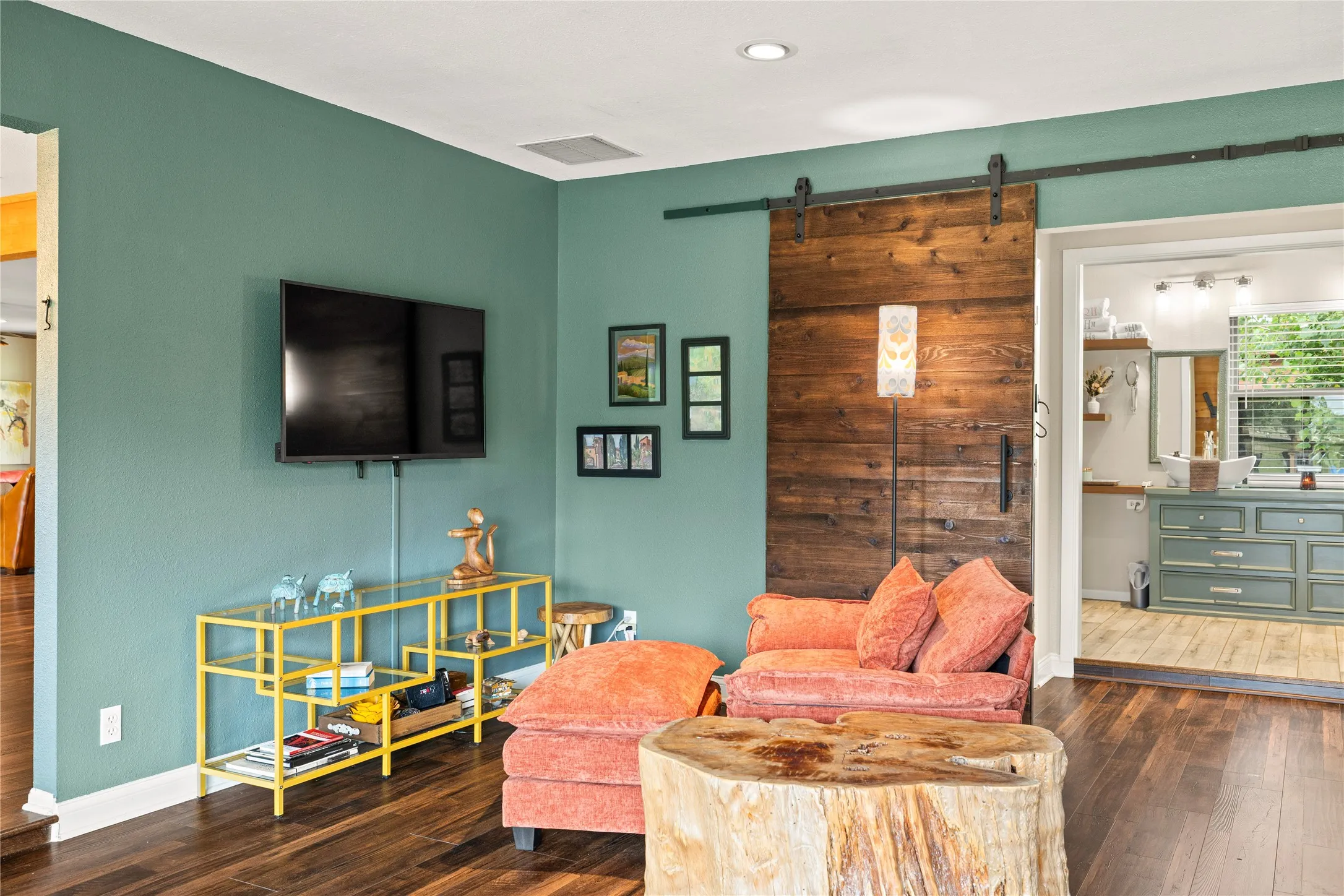 Interior space featuring rich wood-finish flooring, a barn door with dark hardware, and a recessed ceiling light