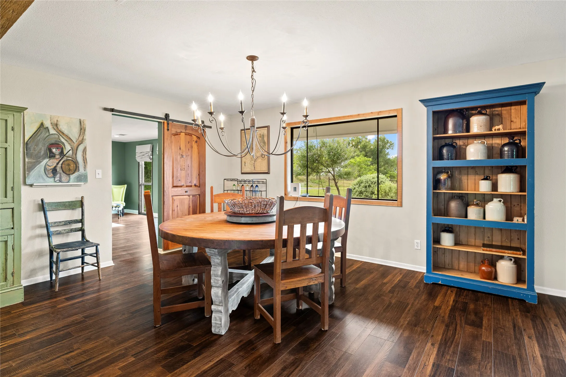 Spacious room with dark wood-finish flooring, a large window, and a sliding barn door