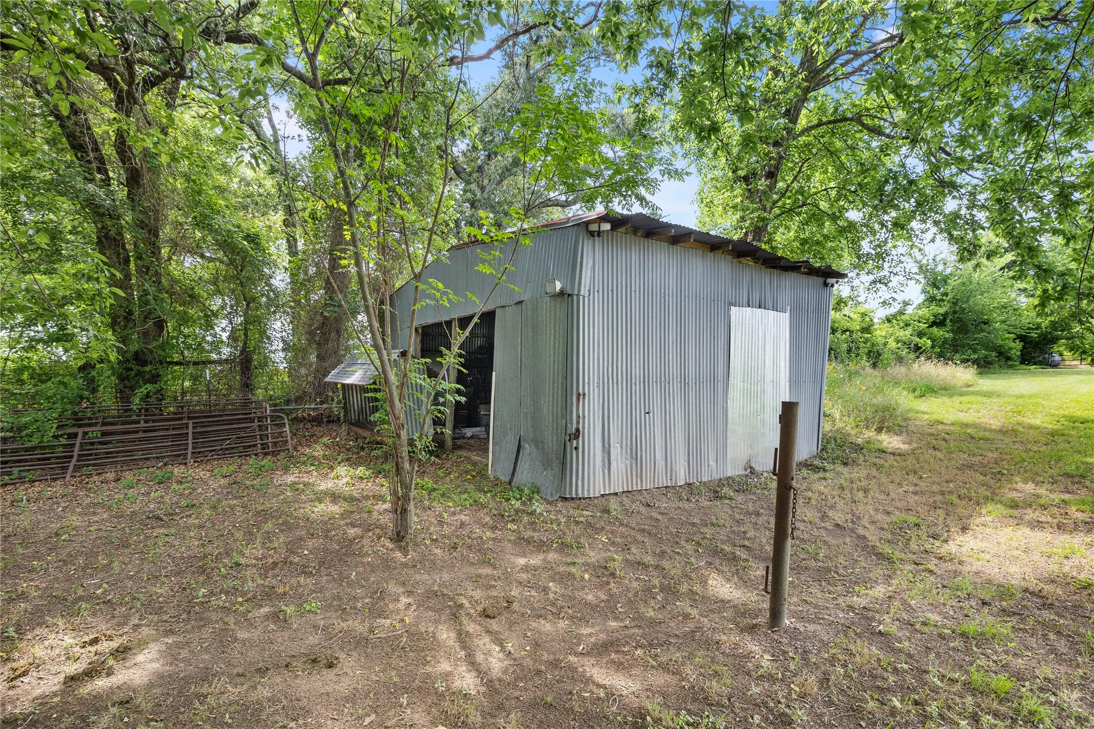 Corrugated metal outbuilding with a single open bay and a separate metal door