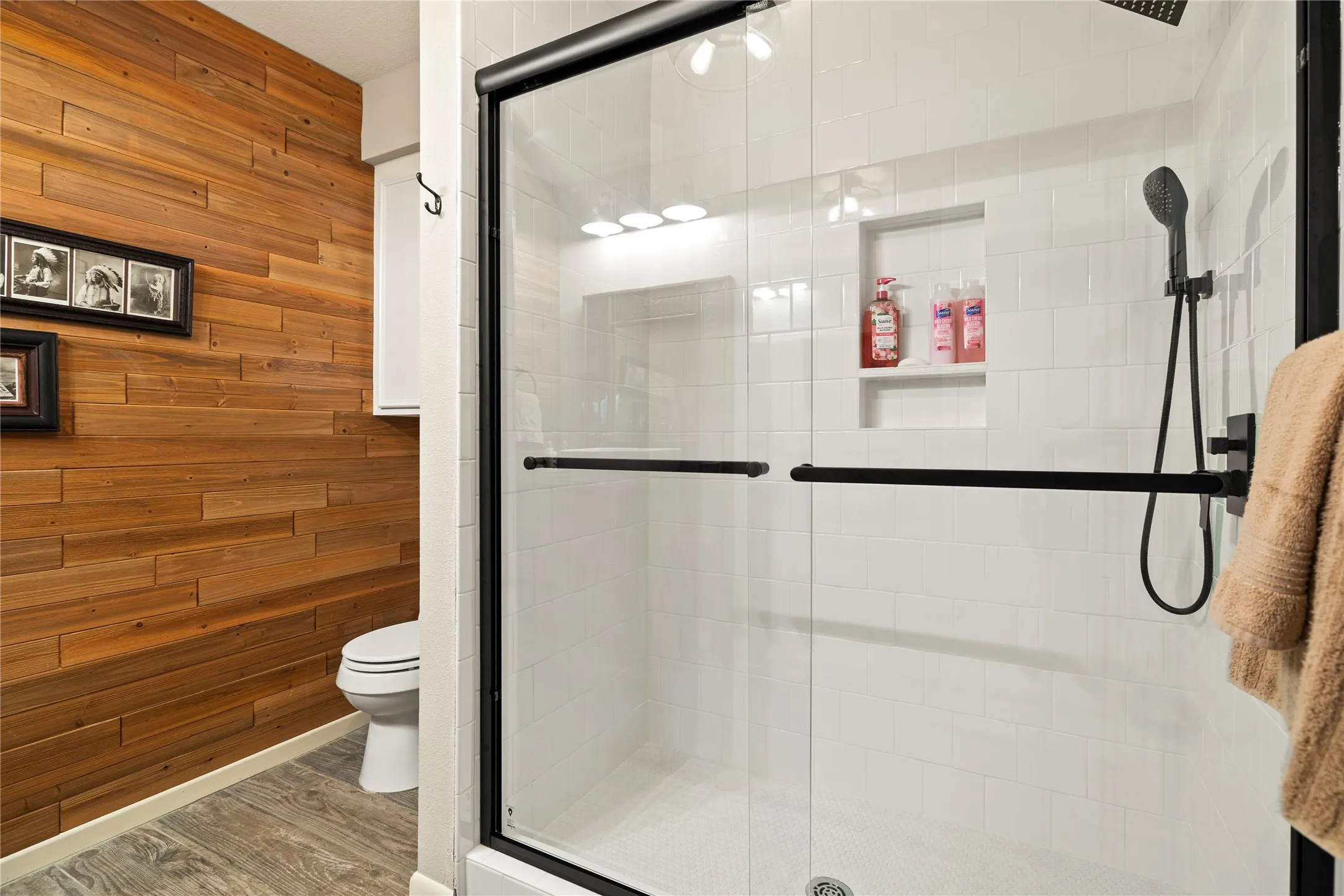 Shower enclosure with black-framed glass doors, white subway tile surround, and a built-in shower niche