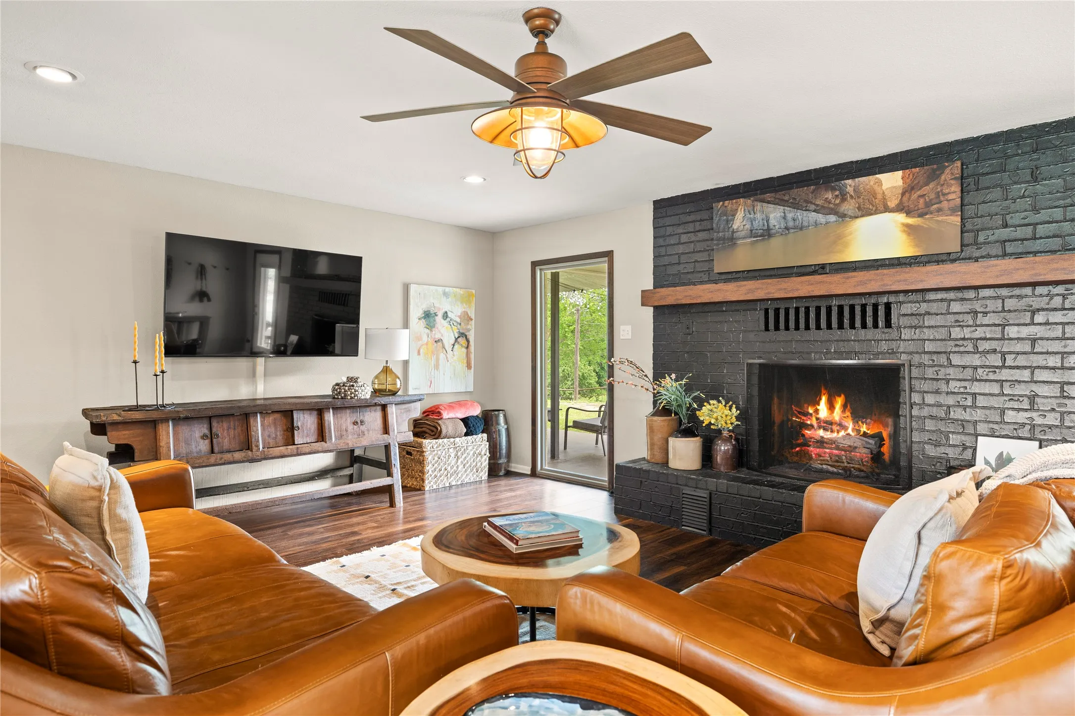 Living area featuring wood-finish flooring and a ceiling fan with integrated lighting