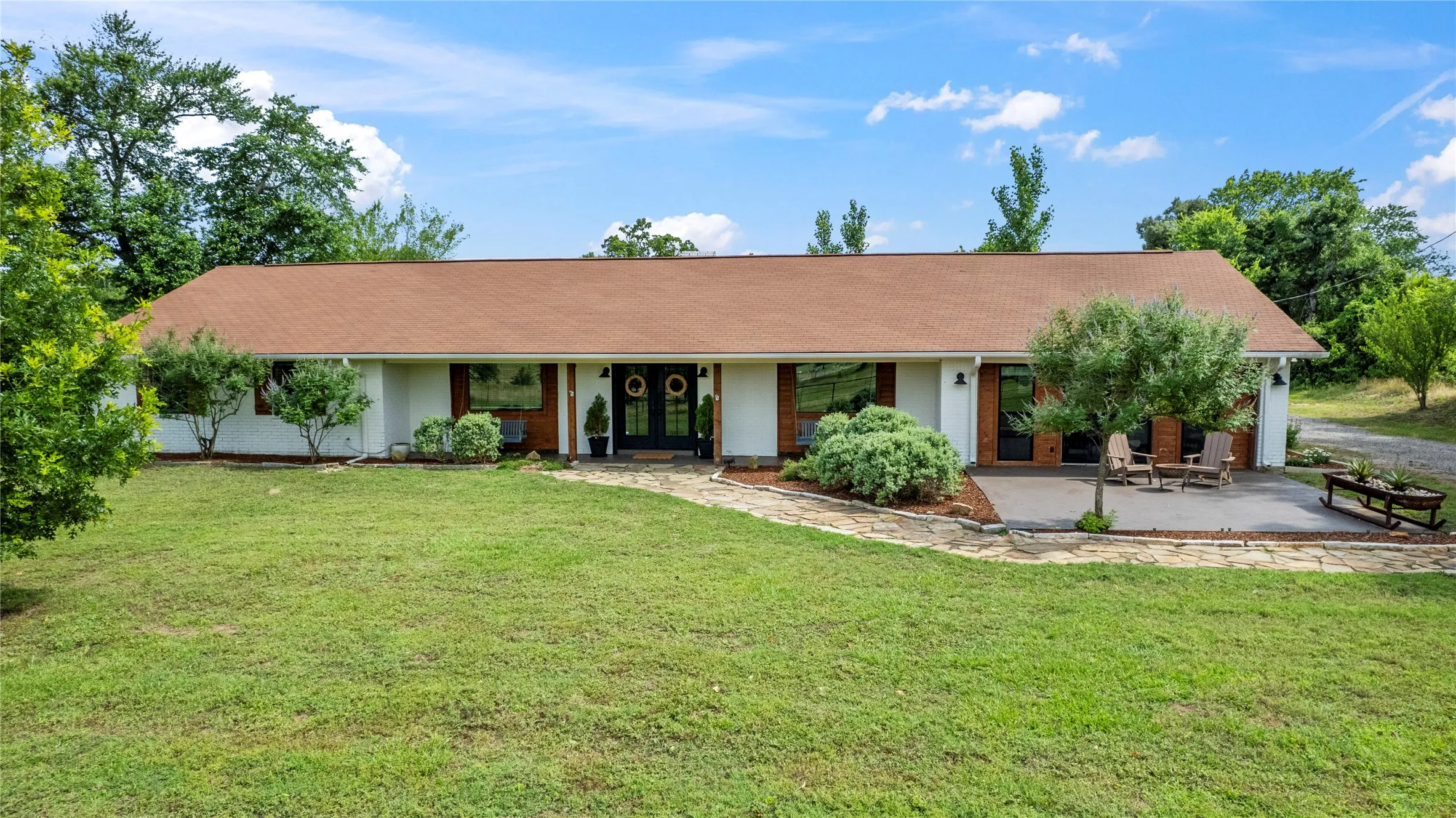 Ranch-style exterior with a brown shingle roof, white siding, and dark-framed windows