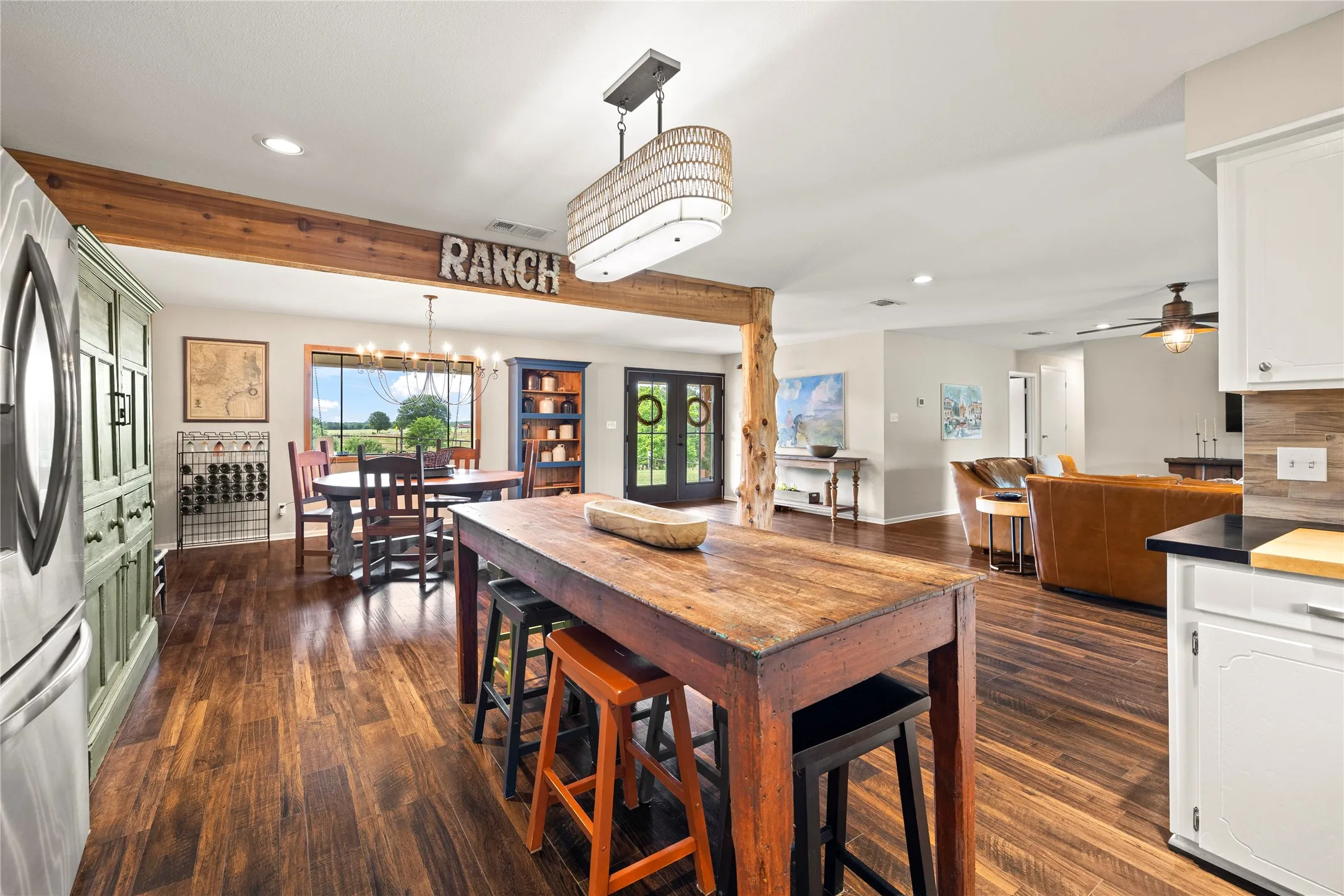 Open-concept living space featuring wood-finish flooring, exposed wood beams, and a dining area with a multi-pane window