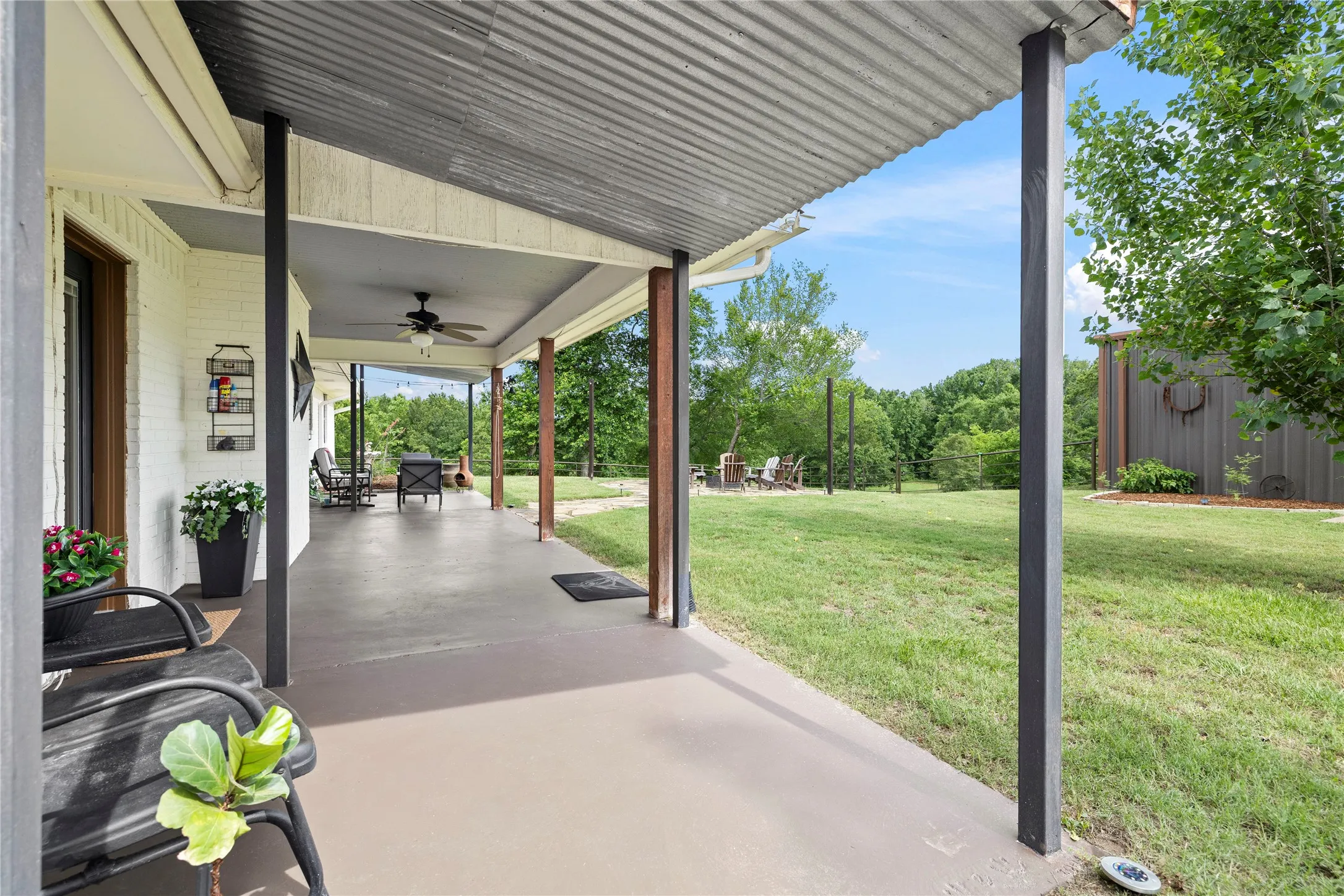 Covered concrete patio featuring a corrugated metal ceiling and exposed wood support beams