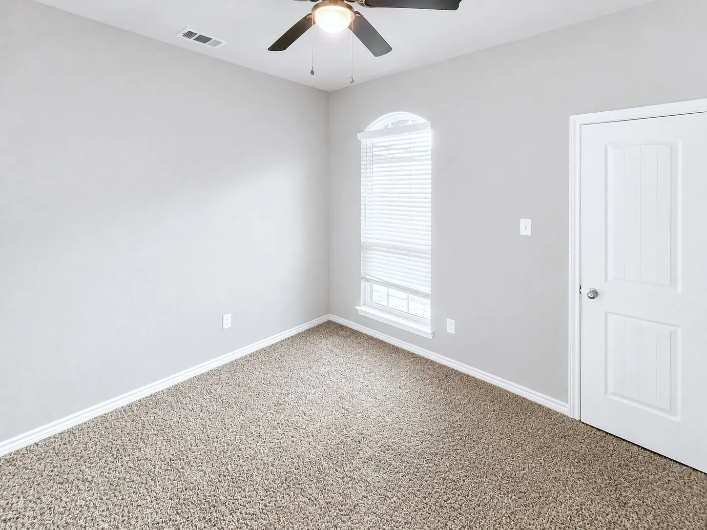 Carpeted interior space with light gray walls, white trim, and a white paneled door