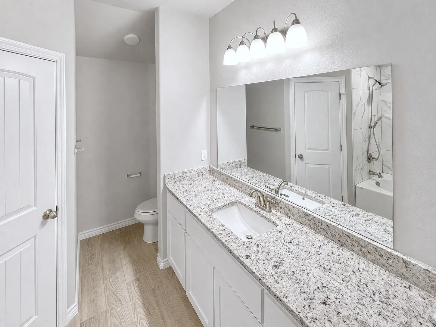 Bathroom vanity featuring a single undermount sink, brushed nickel faucet, and a granite countertop