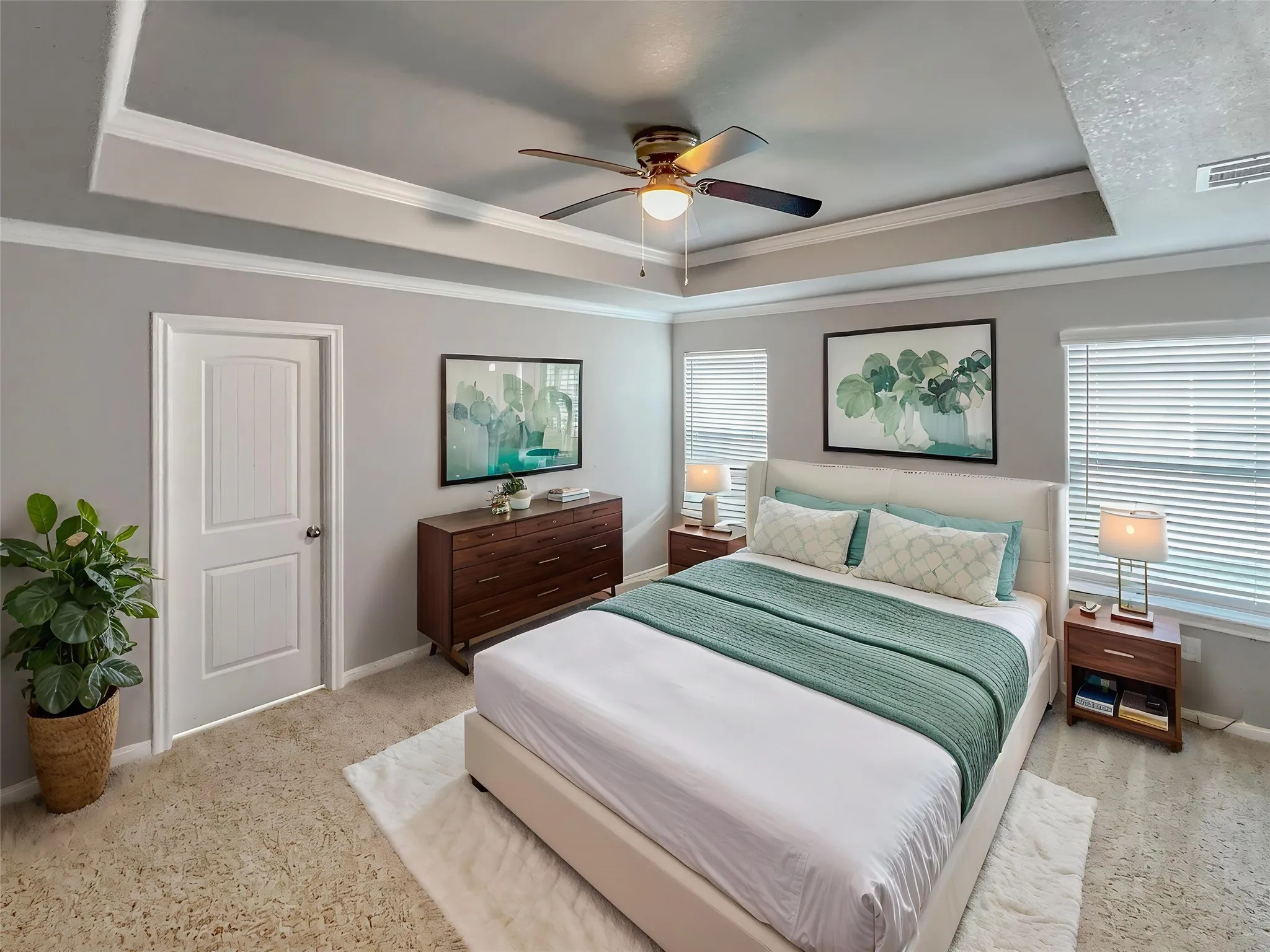 Virtually staged
Recessed tray ceiling with crown molding, ceiling fan, carpet flooring, multiple windows with blinds, and a white panel door