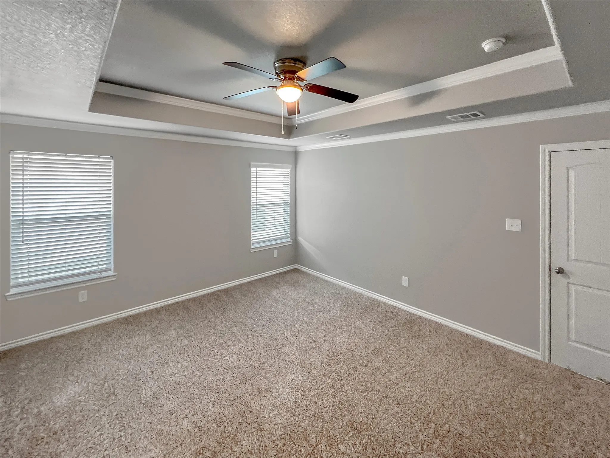 Tray ceiling with decorative crown molding and a ceiling fan light fixture