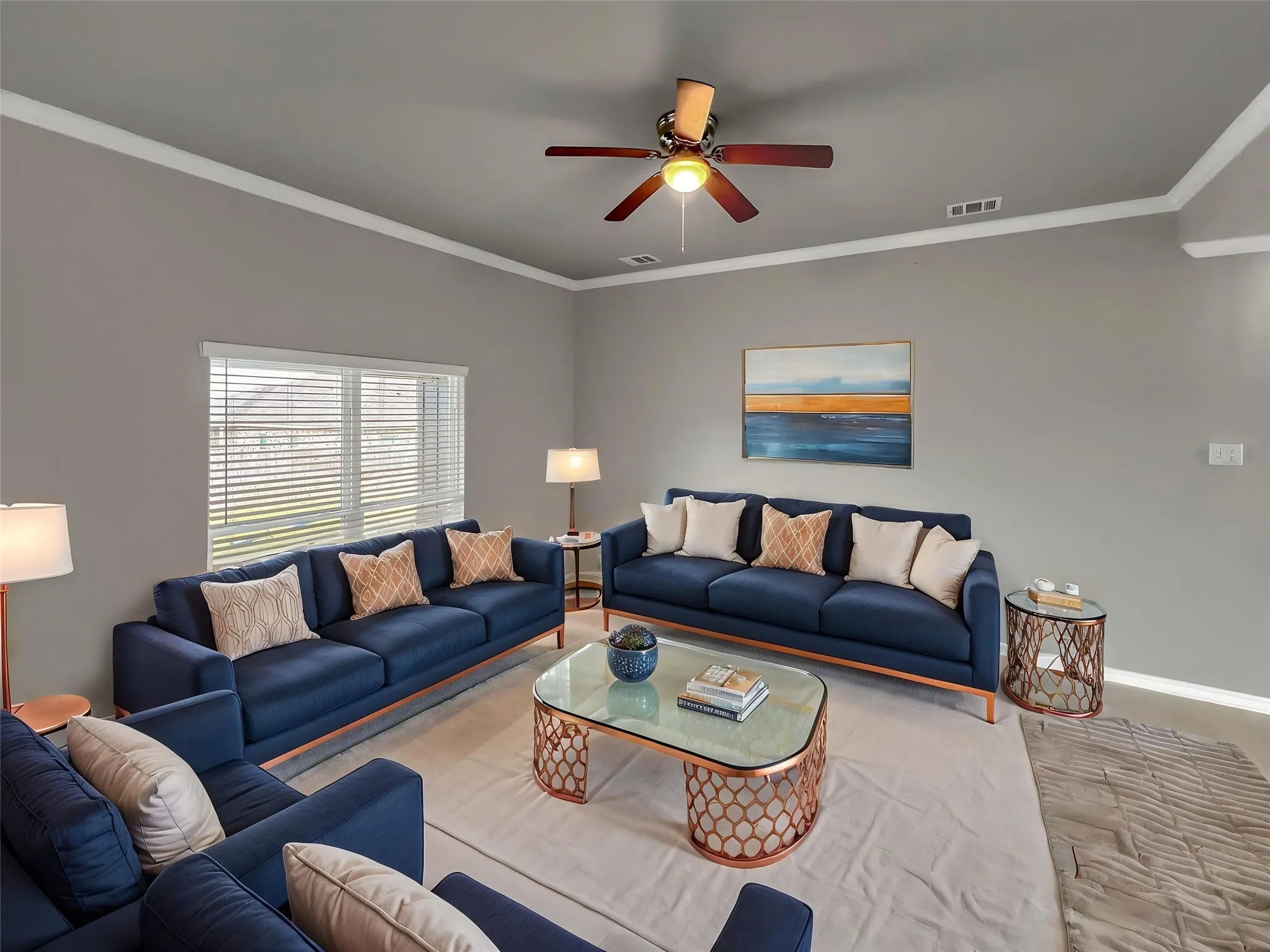 Virtually staged
Spacious living area featuring a ceiling fan with integrated lighting, crown molding, and a large window with horizontal blinds