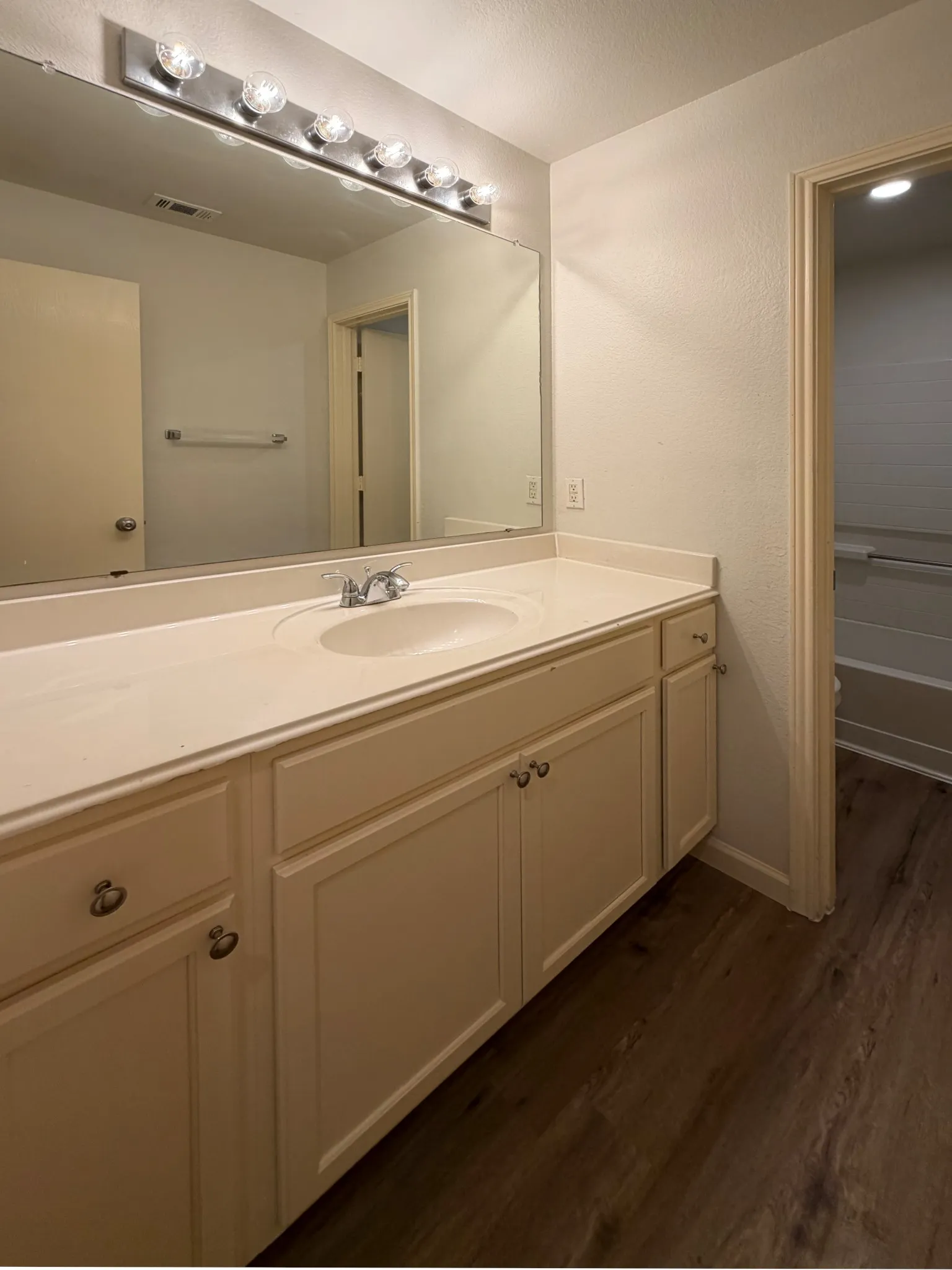 White vanity with an integrated sink, polished chrome faucet, and a large mirror