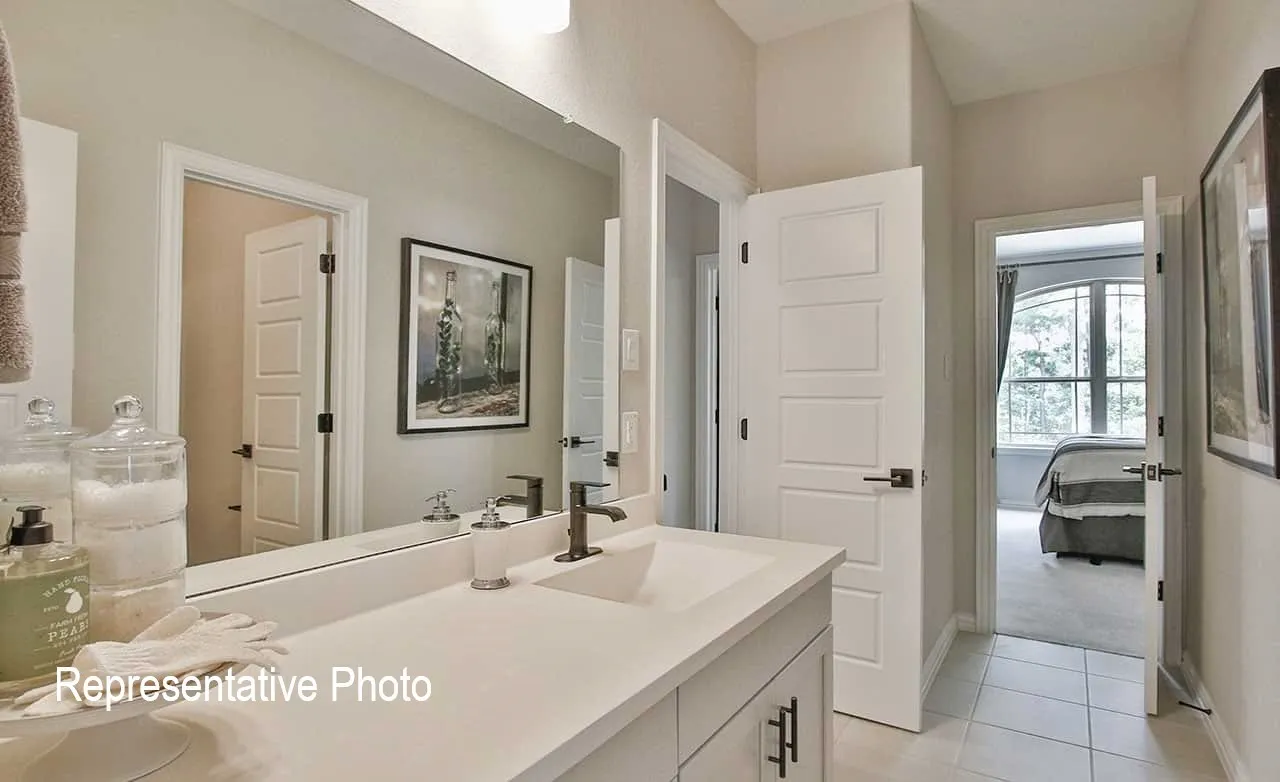 Bathroom vanity featuring a single basin, dark bronze faucet, and a large wall-mounted mirror