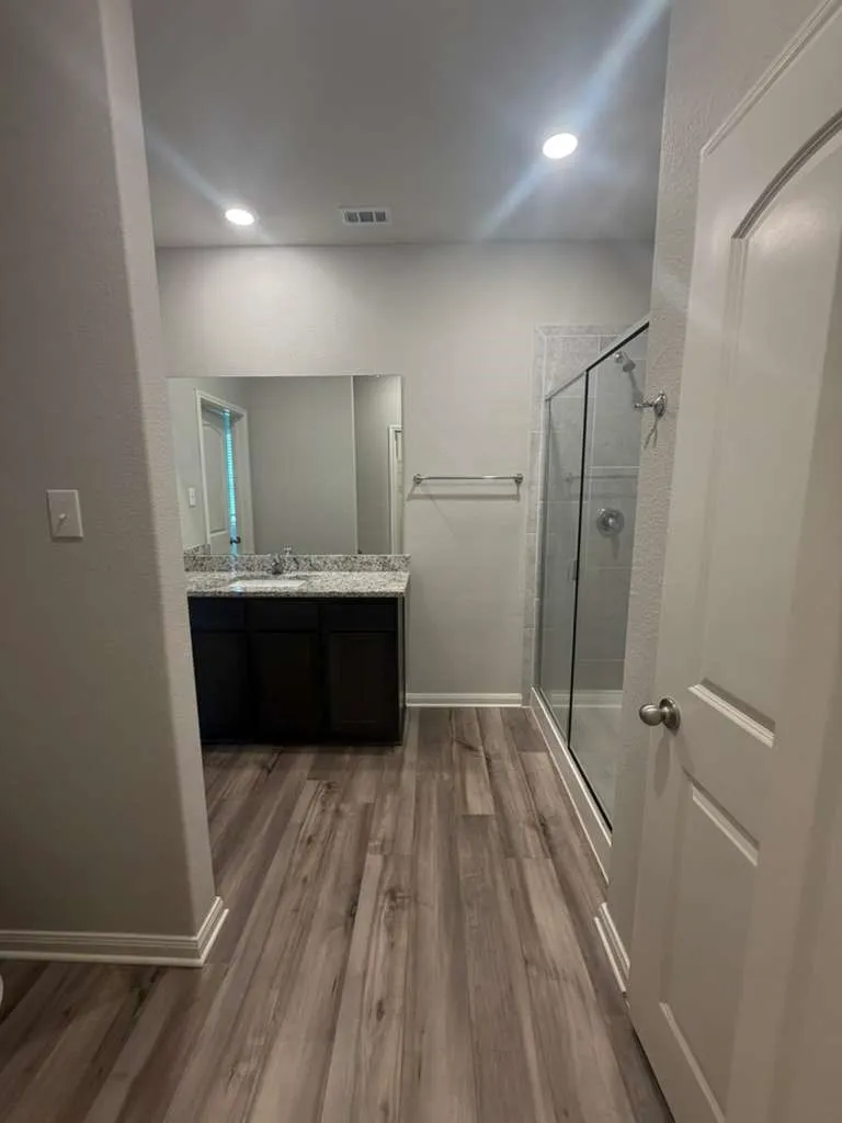 Bathroom featuring wood-finish flooring and a dark wood vanity with a light-colored countertop