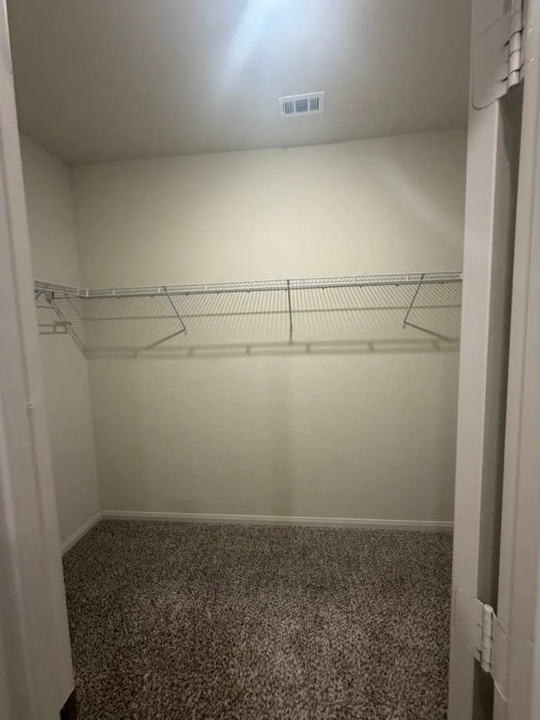 Interior closet featuring warm neutral wall tones and a plush, textured carpet