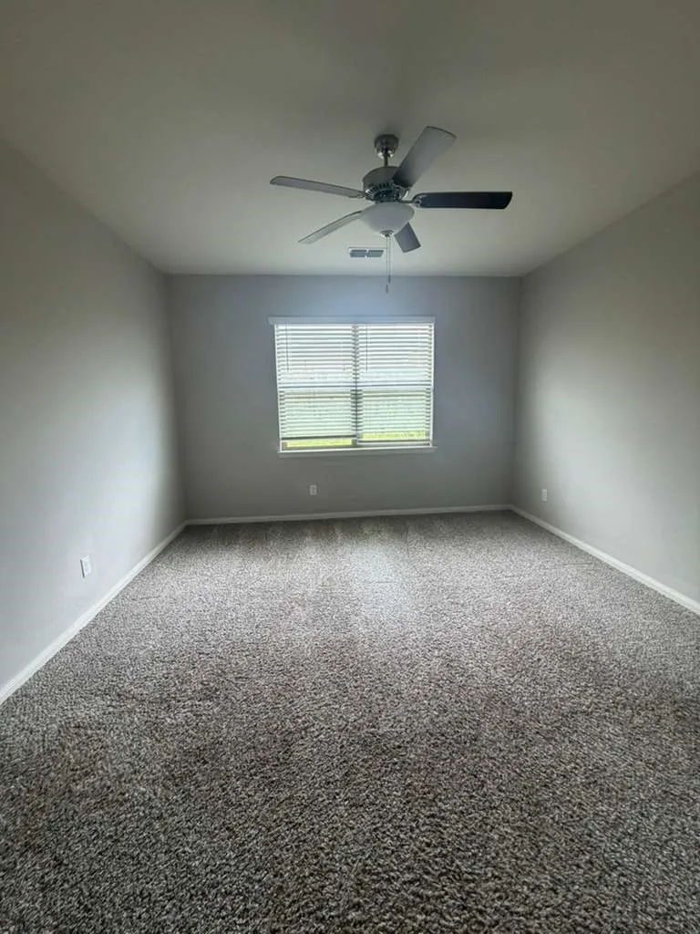 Spacious room featuring neutral tone carpeting and a single window with blinds