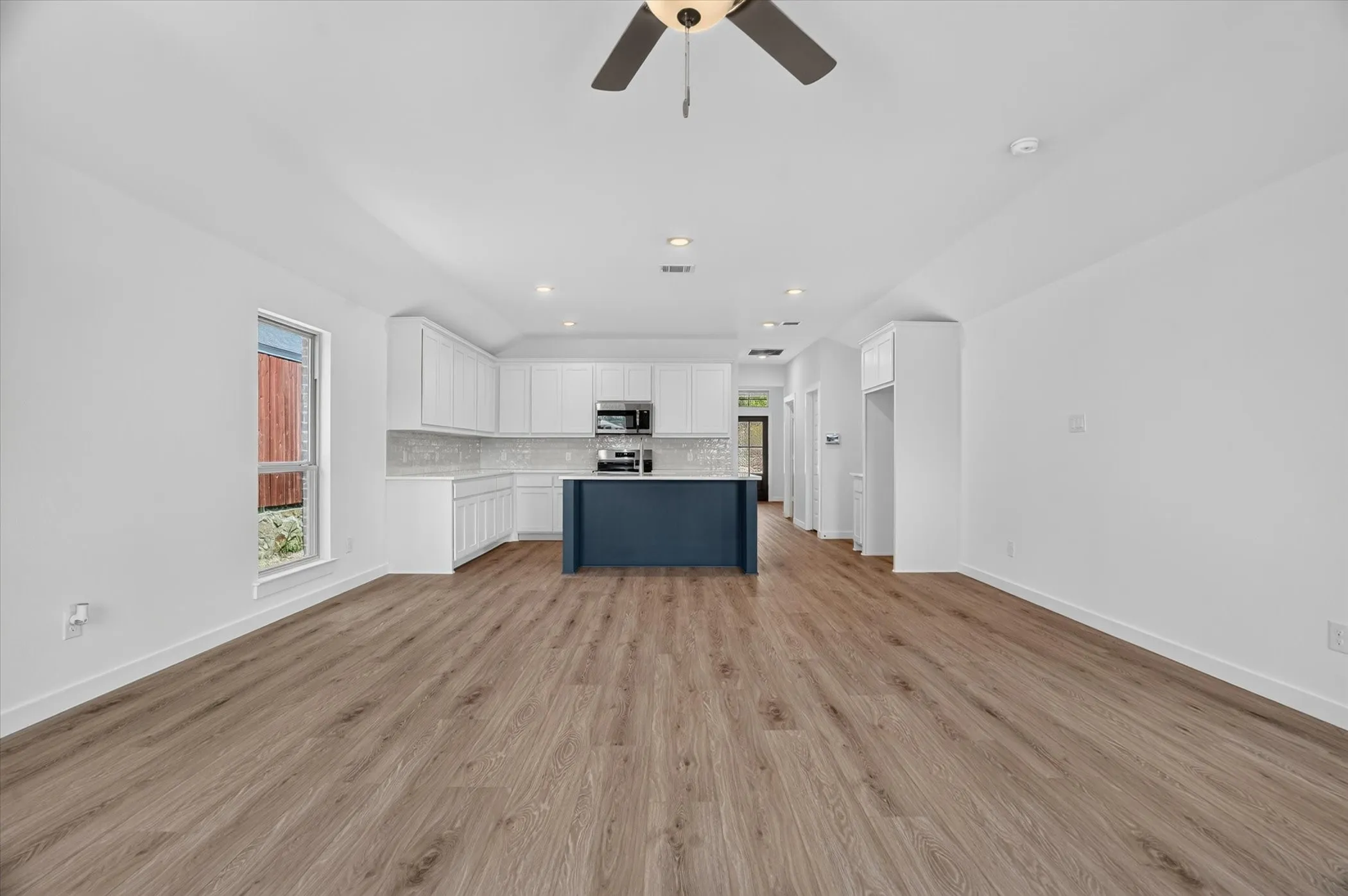 Open-concept living space featuring wood-finish flooring, recessed lighting, and a ceiling fan