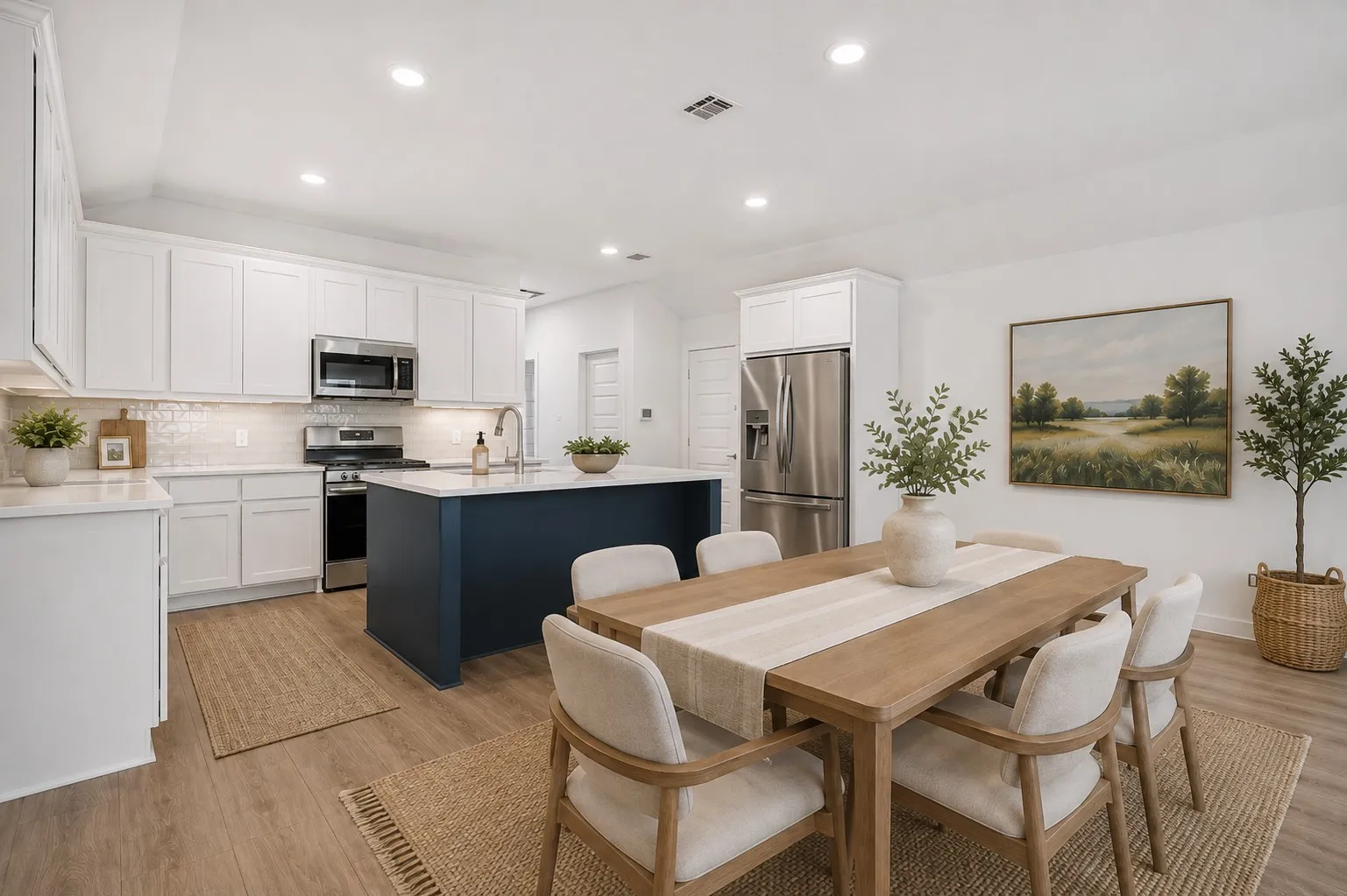 Open-concept kitchen and dining area featuring a dark blue island, white shaker cabinetry, stainless steel appliances, and wood-finish flooring